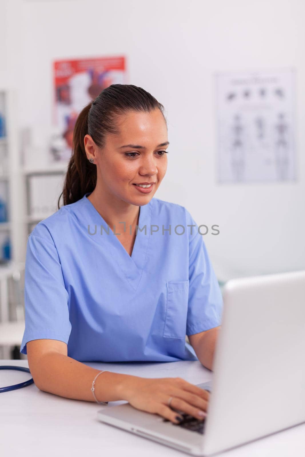 Medical nurse typing on laptop test results of patient in hospital office. Health care practitioner sitting at desk using computer in modern clinic looking at monitor, medicine.