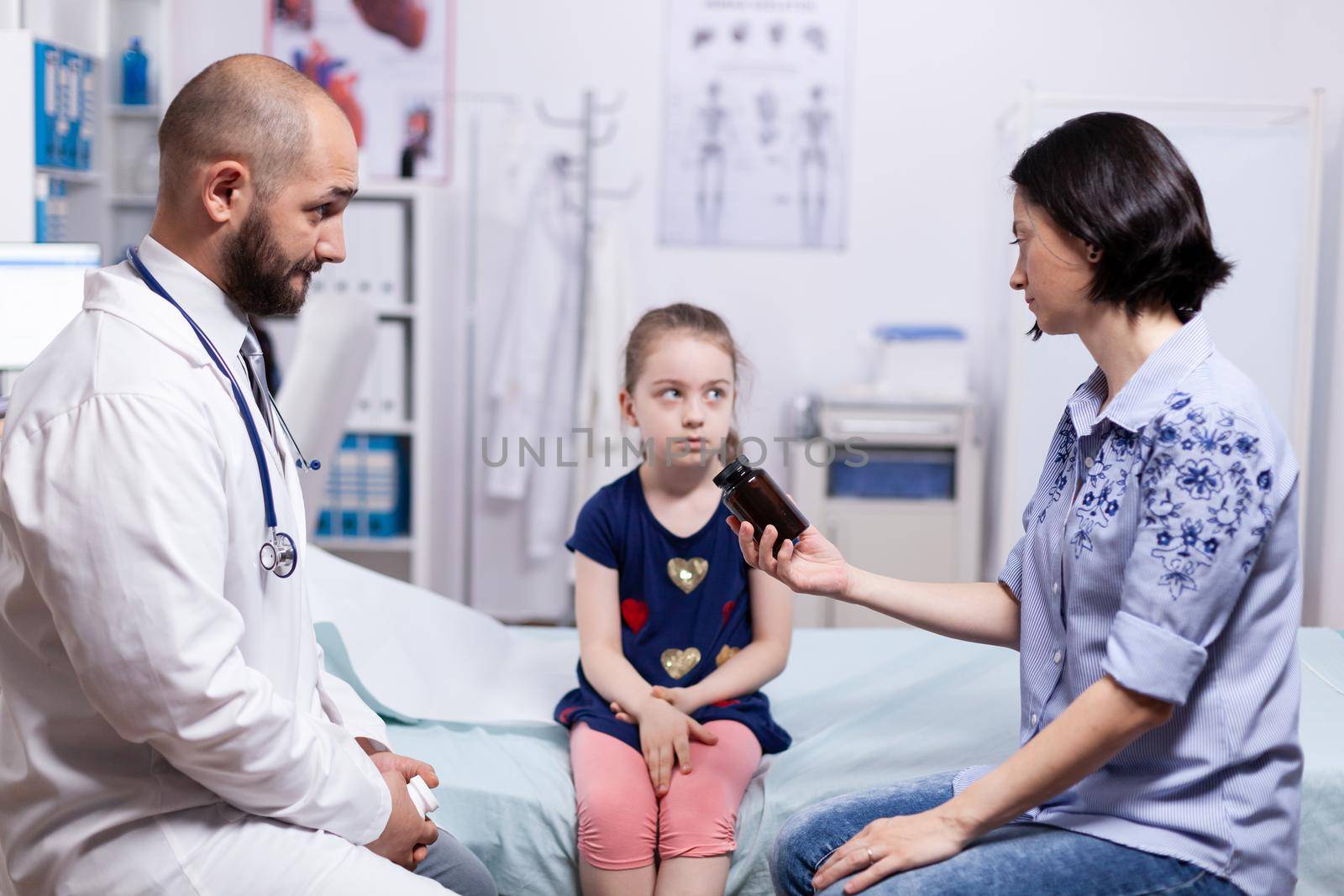 Mother of sick child holding pills bottle from doctor after medical examination. Healthcare physician specialist in medicine providing health care services treatment examination.