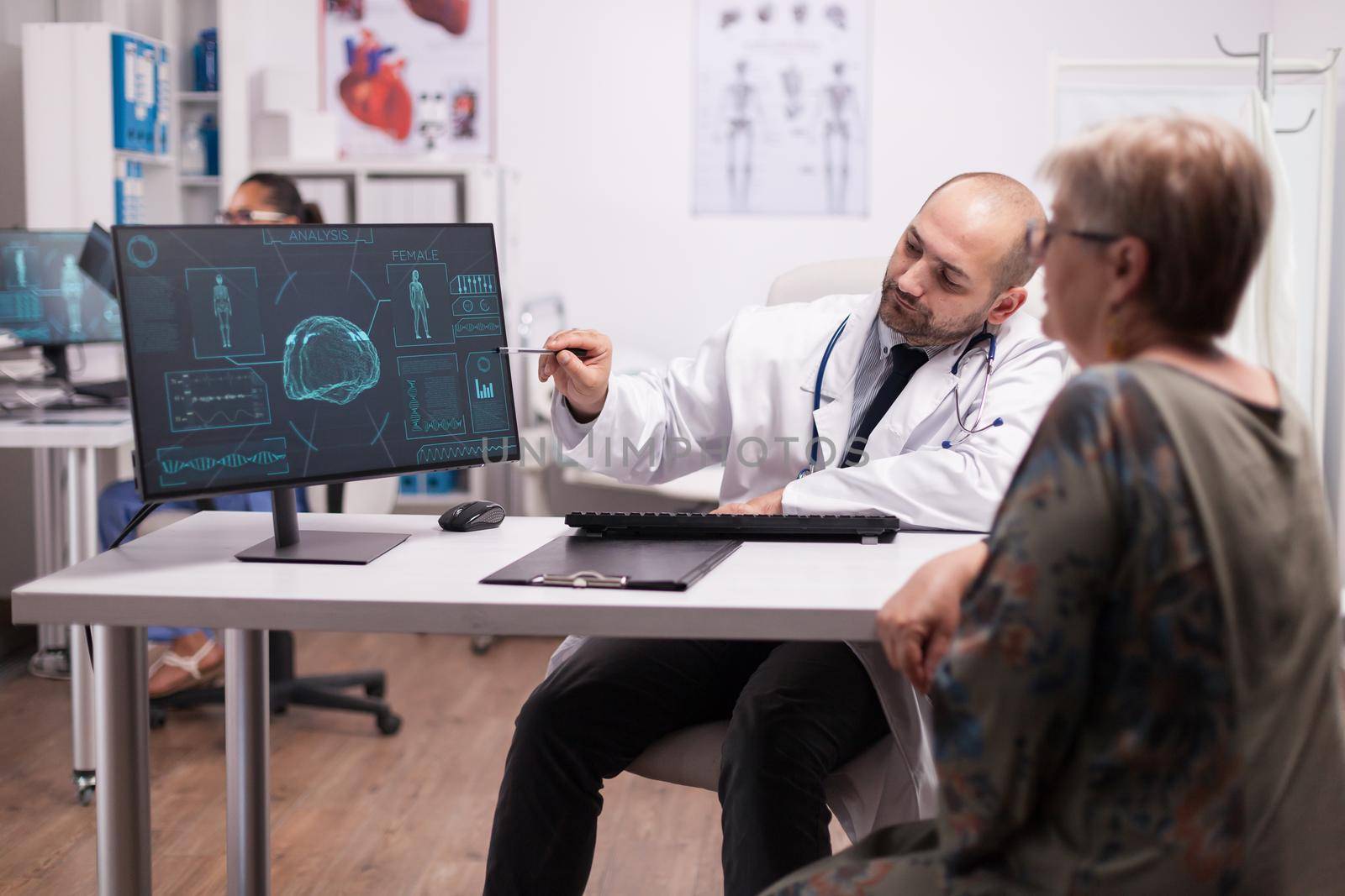 Doctor pointing at ct scan on computer for senior patient during visit after brain surgery. Diagnosis for head trauma. Medic wearing white coat and stethoscope.