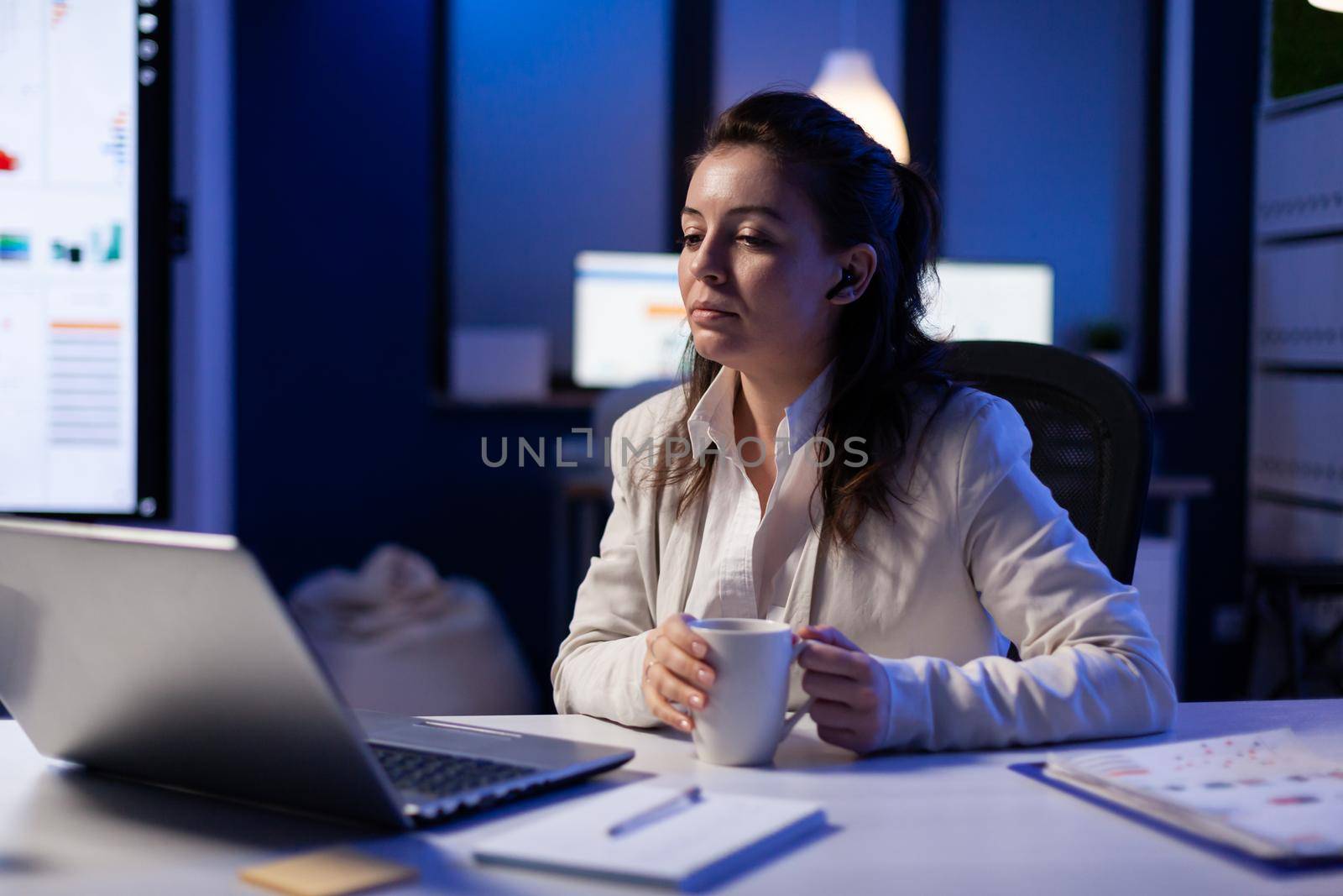 Workaholic businesswoman analysing economic statistics late at night in business office. Tired woman planning marketing project before deadline using modern technology network wireless