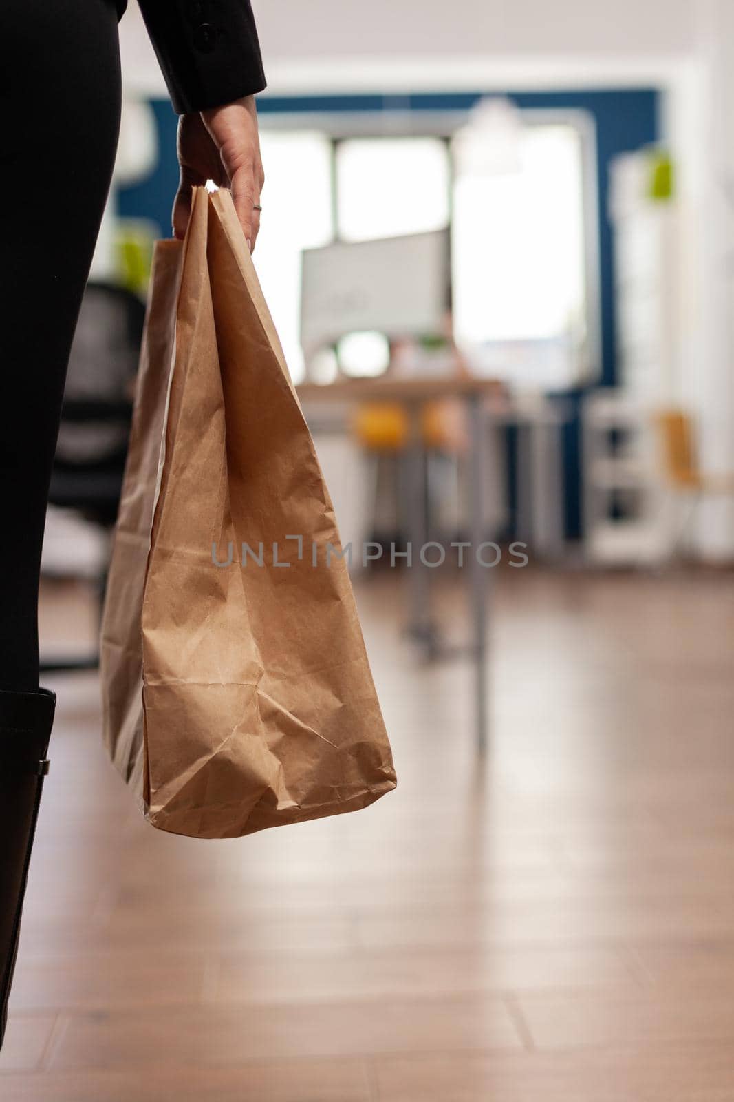 Businesswoman holding paper bag with takeaway food meal order putting on desk by DCStudio