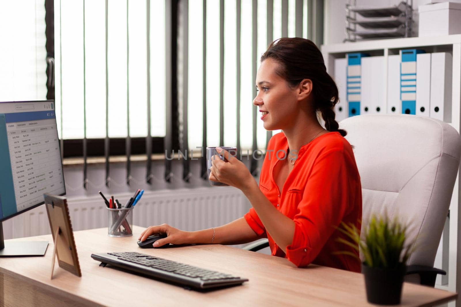 Businesswoman corporate entrepreneur concentrated looking at computer screen in office workplace. Successful confident woman in marketing sitting at desk in workplace using computer.
