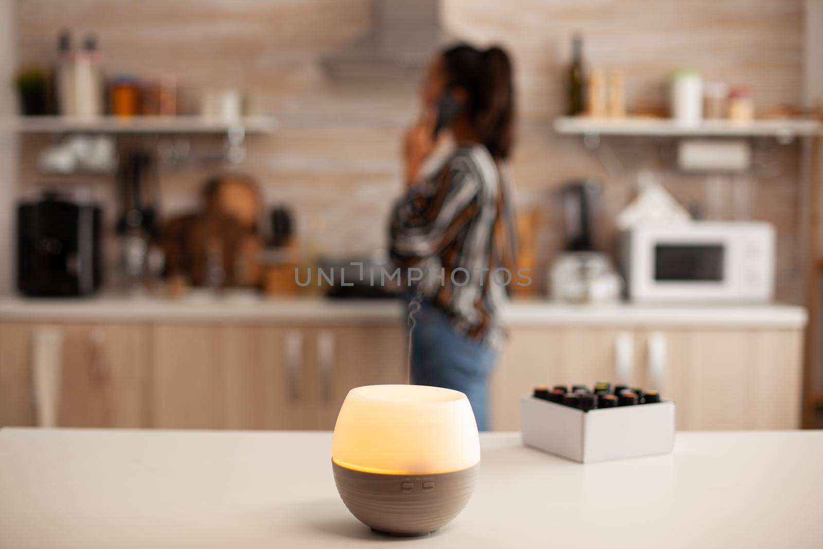 Having a conversation unsing smartphone and ejoying aromatherapy from diffuser with essential oils. Aroma health essence, welness aromatherapy home spa fragrance tranquil theraphy,