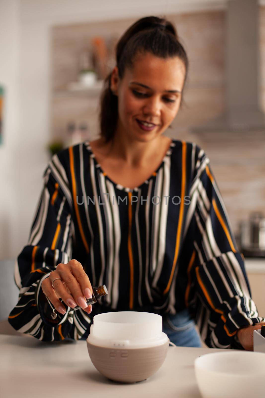 Woman adding essential oils into diffuser for aromatherapy. Aroma health essence, welness home spa fragrance tranquil theraphy, therapeutic steam, mental health treatment