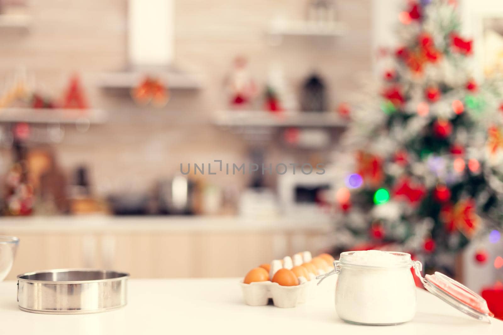 Ingredients for preparation of delicious cookies on table in empty room. Kitchen on christmas day with nobody in the room decorated with x-mas tree and garlands