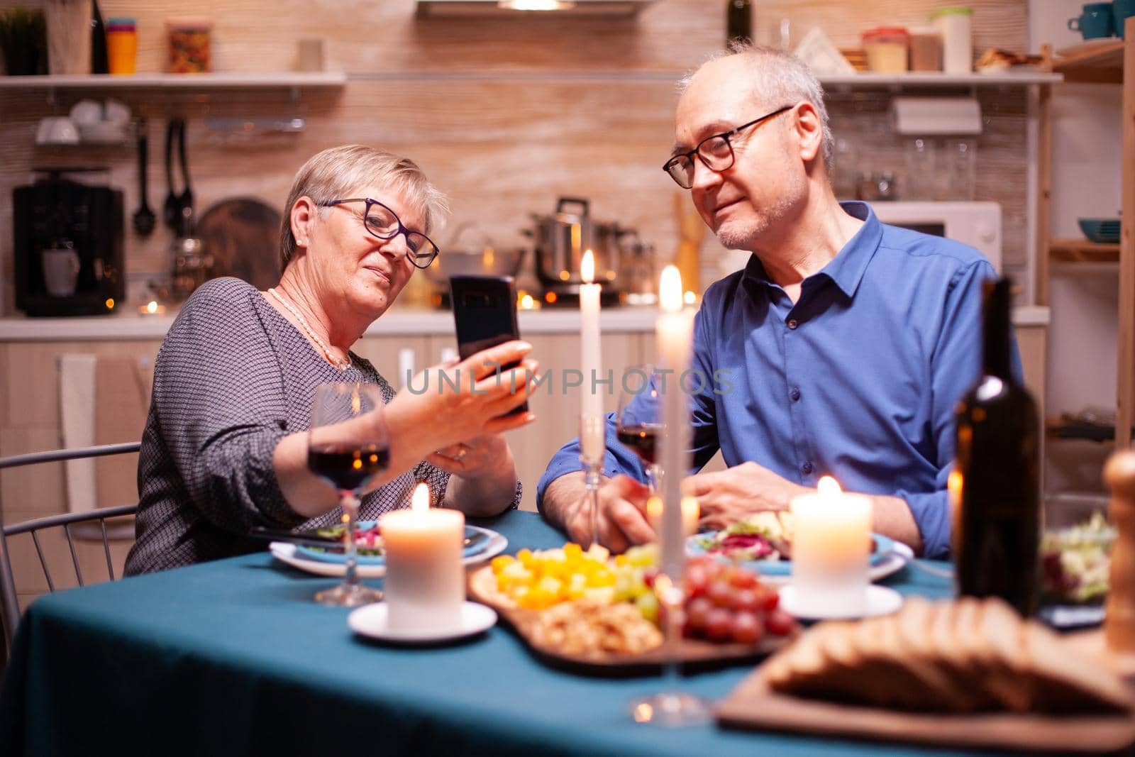 Old couple using phones in the kitchen by DCStudio