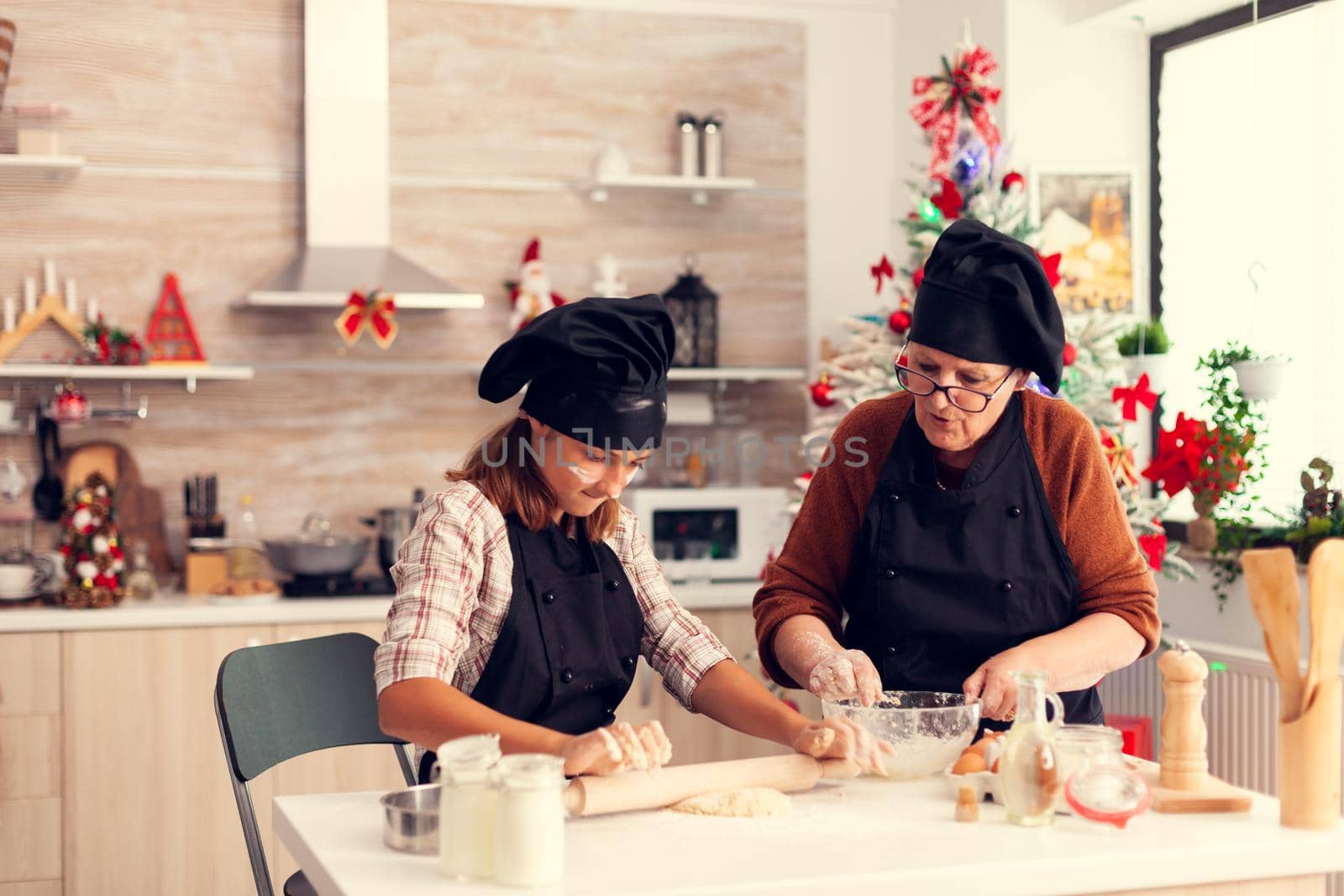 Niece and grandmother wearing apron on christmas day knead dough by DCStudio