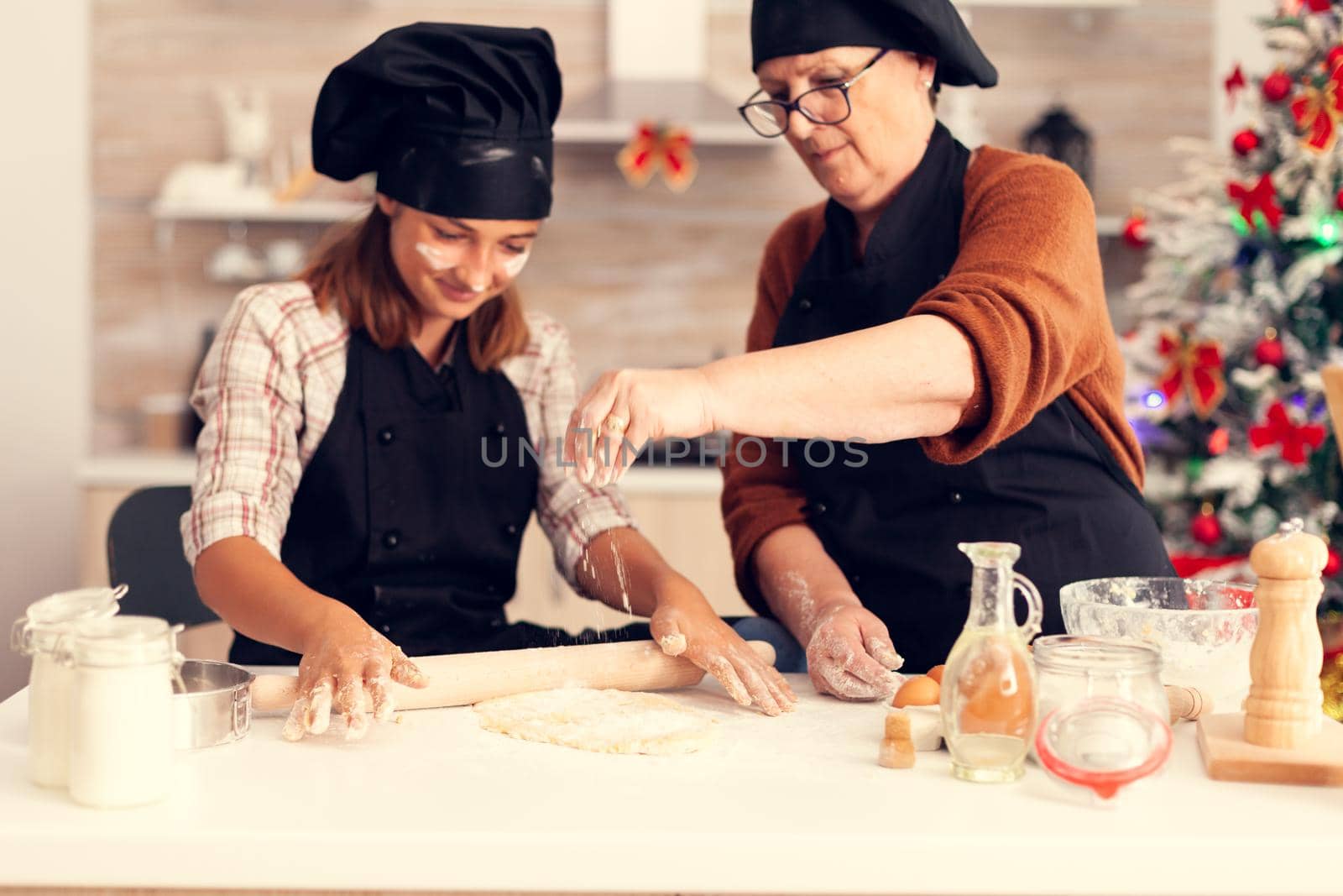 Granddaughter in apron preparing cake on christmas day by DCStudio