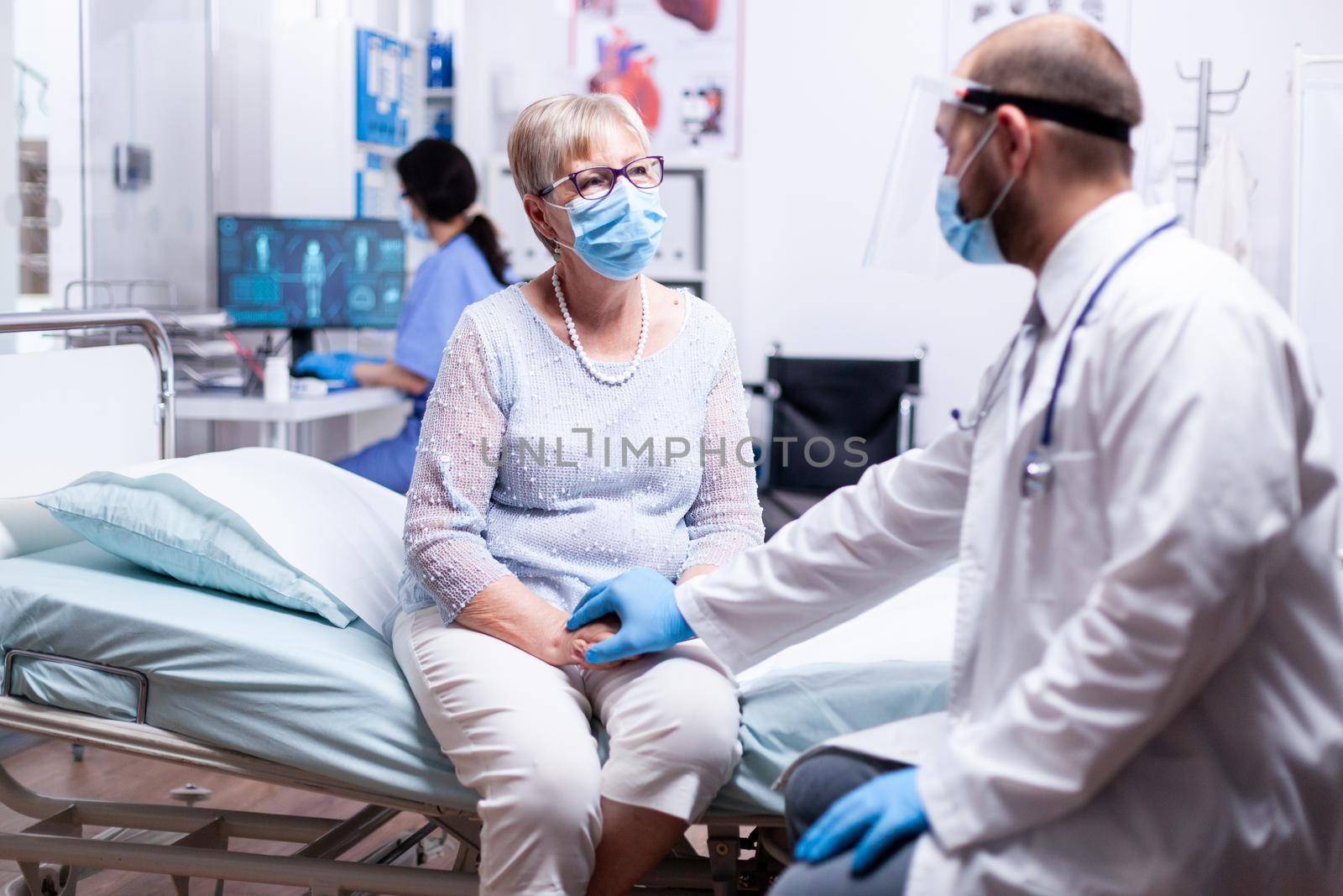 Doctor holding senior woman patient hand giving encouragement during consultation in hospital room. Converstation with medical stuff clinic medicine healthcare