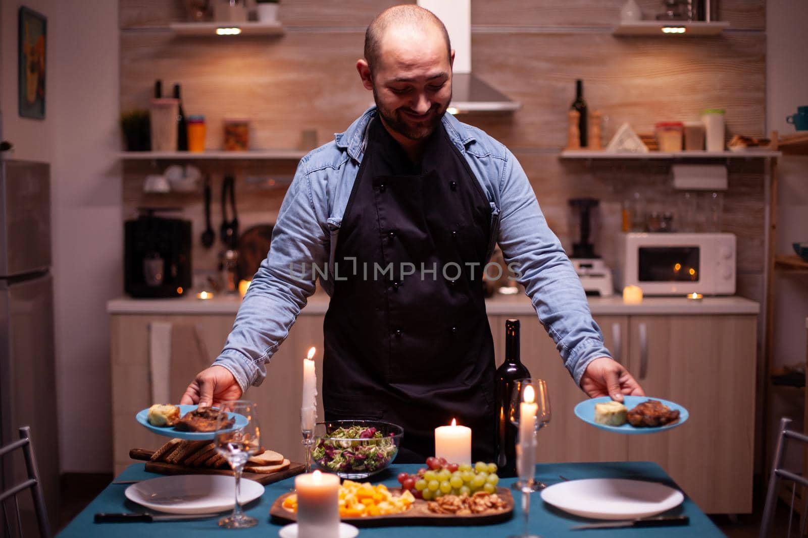 Husband holding plates with food for romantic dinner in dining room with wife. Man preparing festive dinner with healthy food, cooking for his woman a romantic dinner,