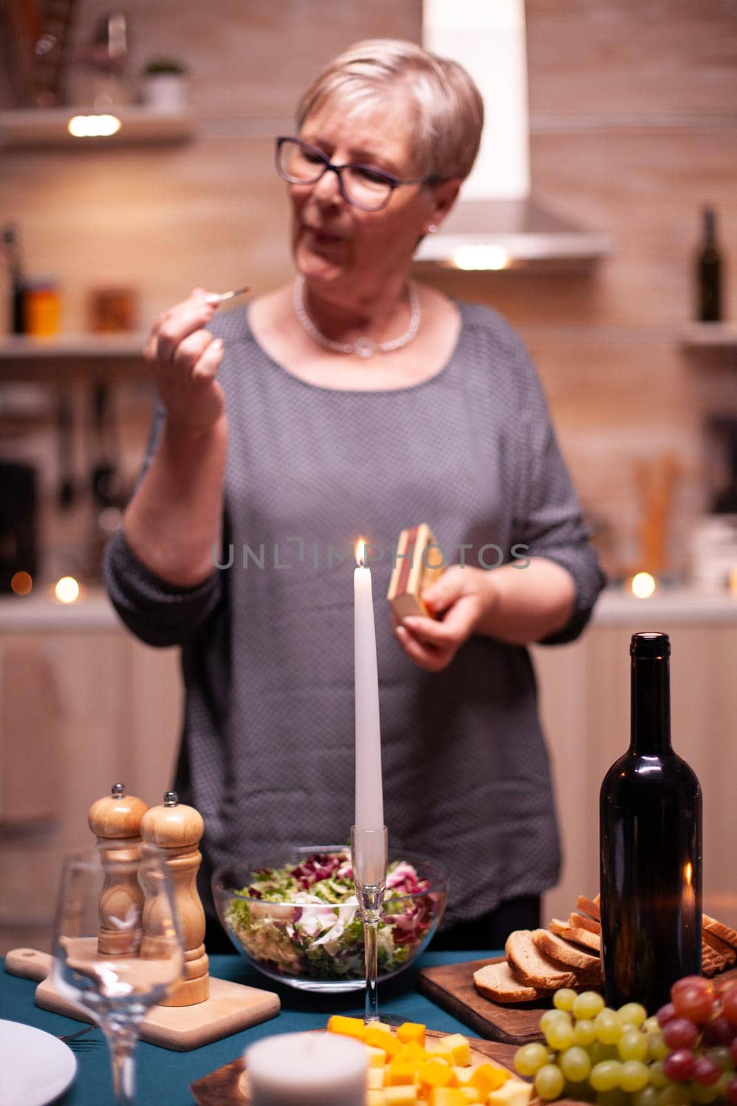 Pensioner preparing for festive dinner with husband. Elderly woman waiting her husband for a romantic dinner. Mature wife preparing meal for anniversary celebration.