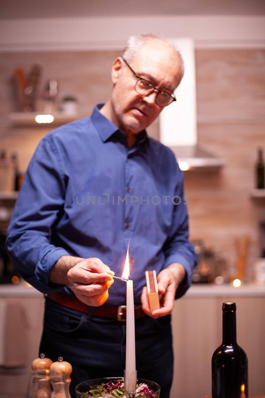 Senior man lighting candle with matches by DCStudio