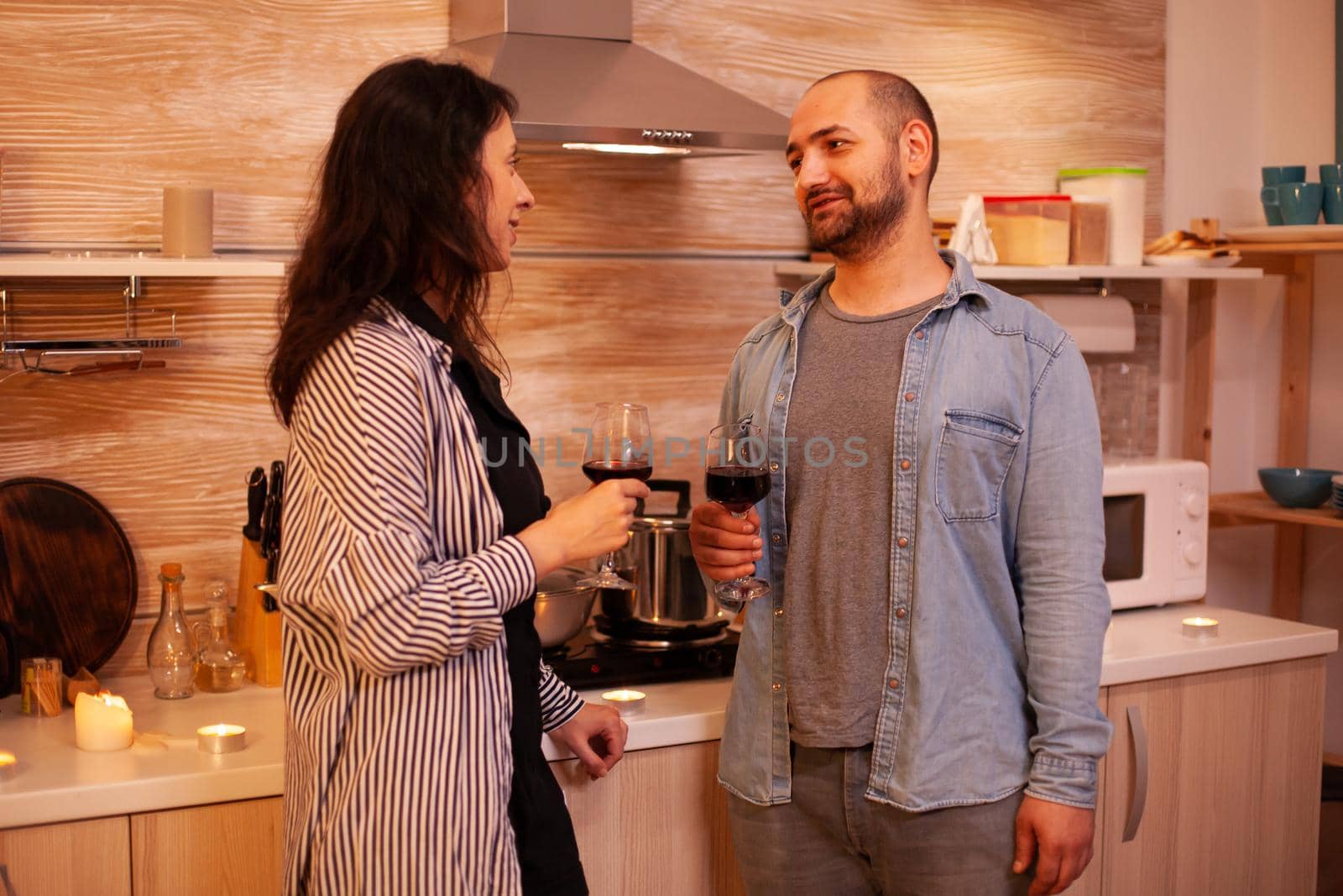 Man and woman having fun during date drinking wine. Adult couple having romantic date at home, in the kitchen, talking, smiling, enjoying the meal in dining room.