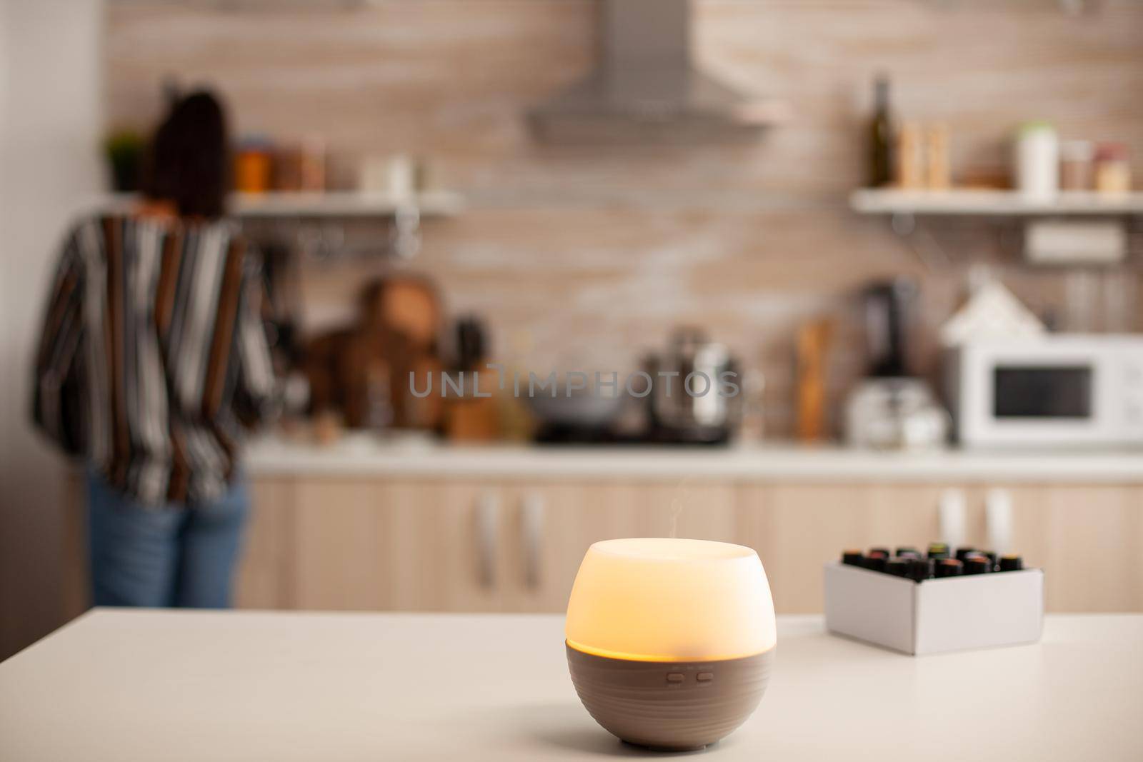 Woman in the kitchen with essential oils diffuser by DCStudio