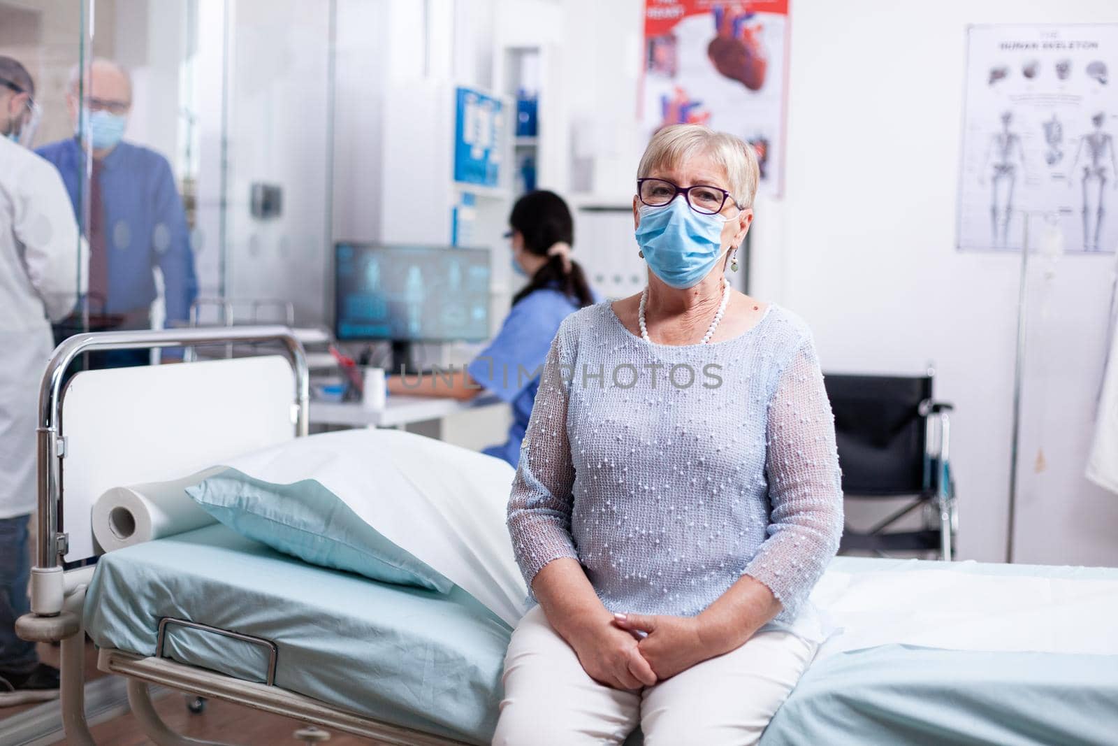 Elderly woman wearing face mask against covid while waiting for doctor in hospital cabinet for medical appoinmnet. Global health crisis, medical system during pandemic, sick elderly patient.