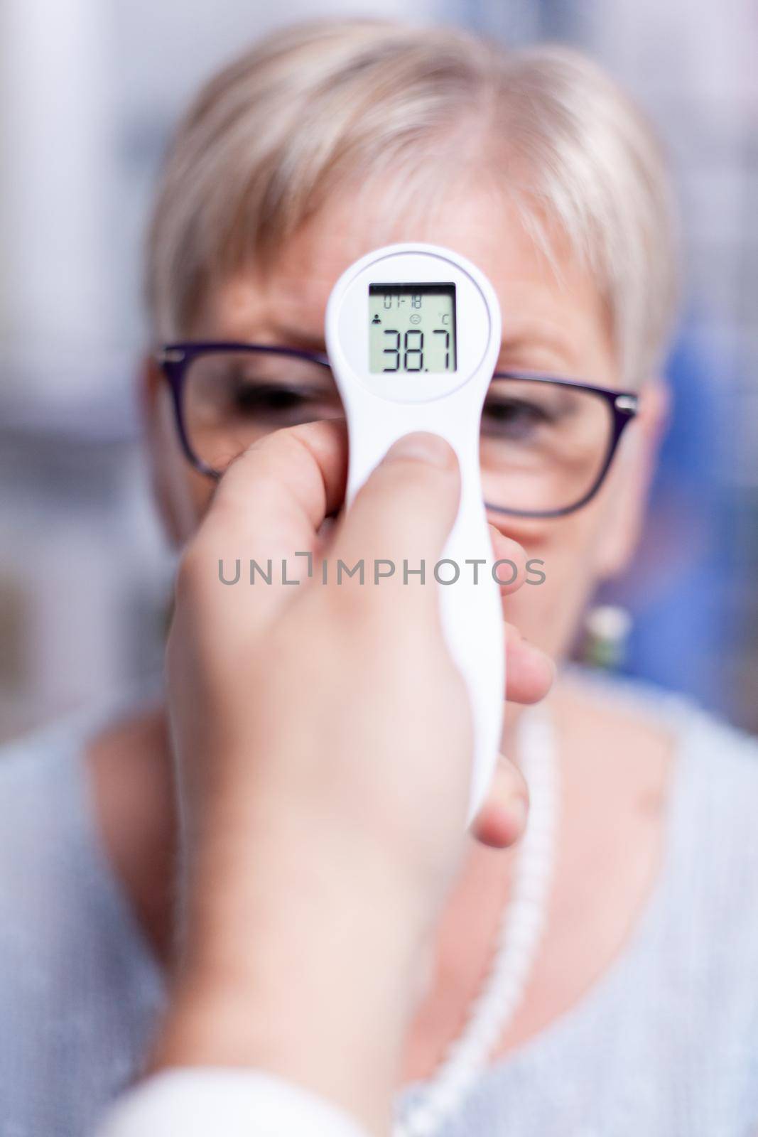 Thermometer showing body temperature of sick mature patient woman in hospital during medical examination. Consultation for infections and disease during global pandemic,flu, tool, sickness.