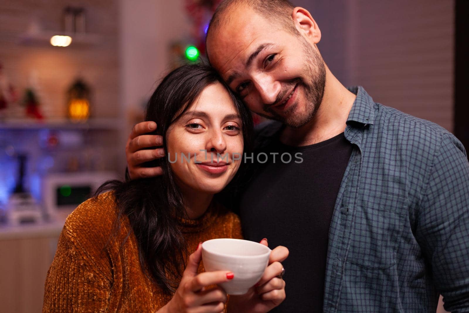 Portrait of happy couple looking into camera hugging enjoying christmas holiday together in xmas holiday. Joyful family smiling while celebrating wintertime during winter season