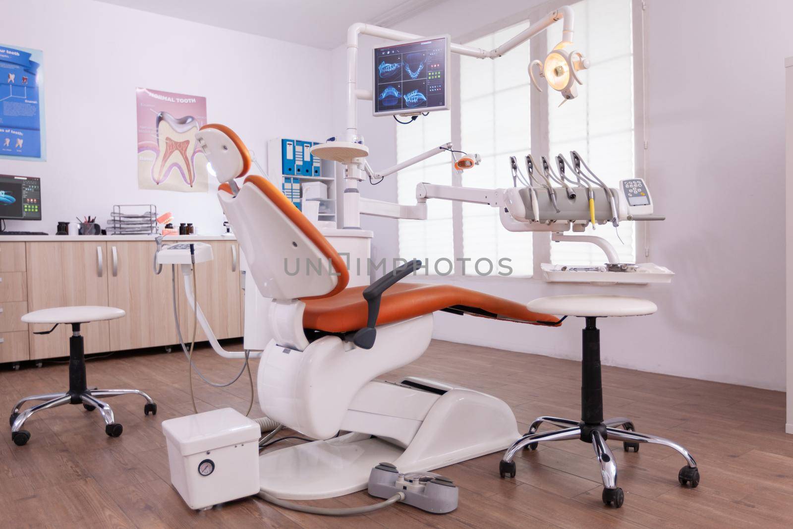 Empty orthodontist stomatology office with nobody in it. Light modern equipped orthodontic workplace, teeth hygiene and care. Hospital dental health. Tooth xray image on monitor