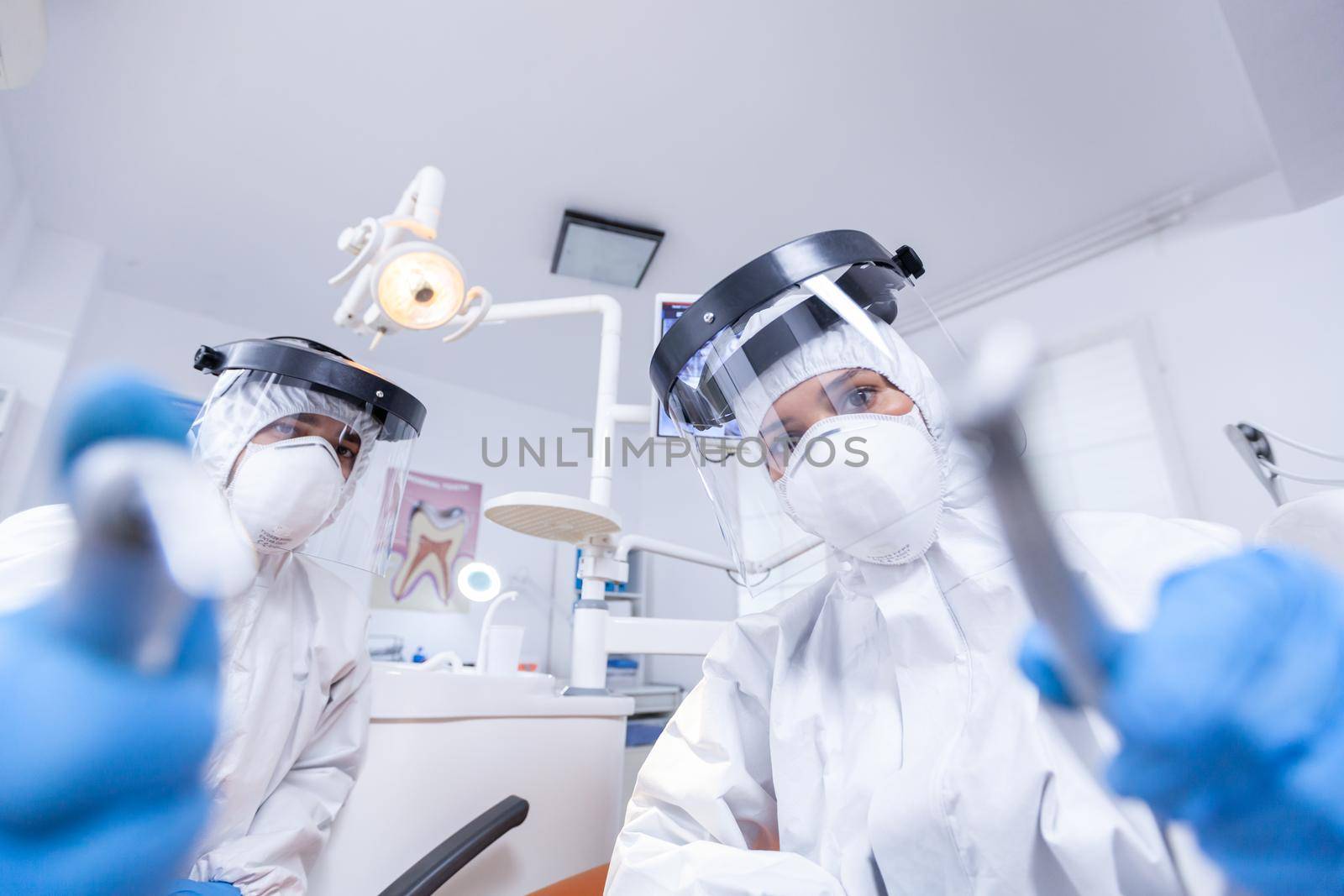 Dental team leaning over patient to work on patient gums by DCStudio