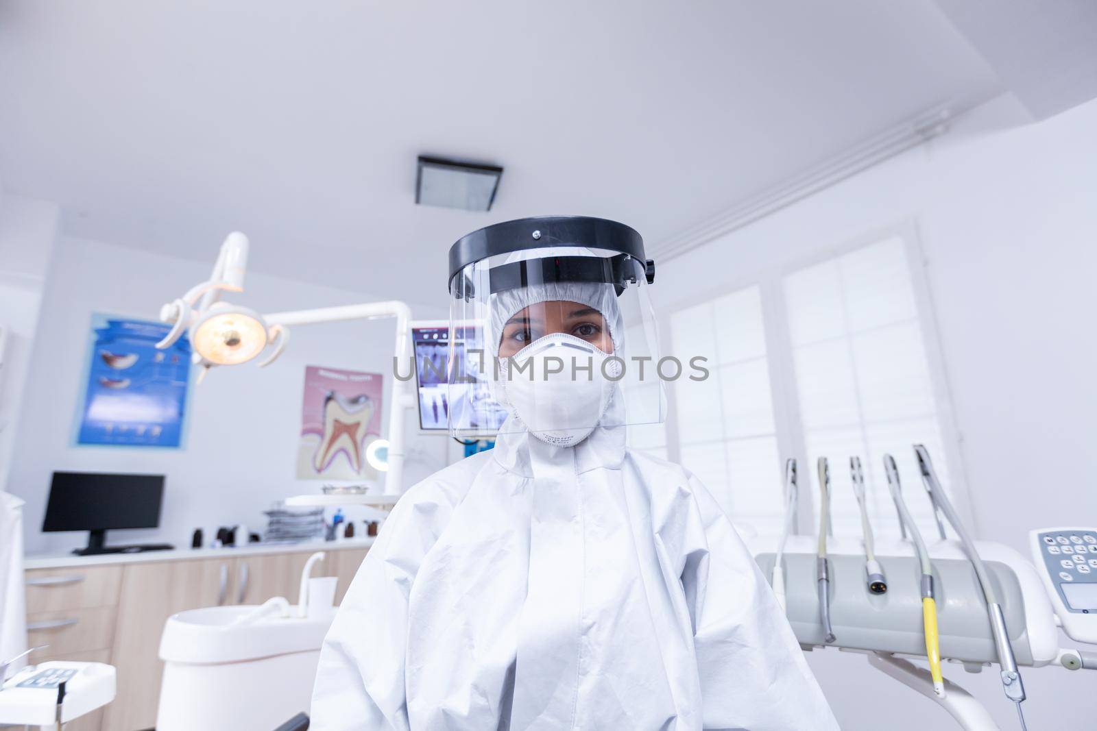 Patient pov of dentist in protective gear against infection with covid virus in dental office. Stomatolog wearing safety gear against coronavirus during heatlhcare check of patient.