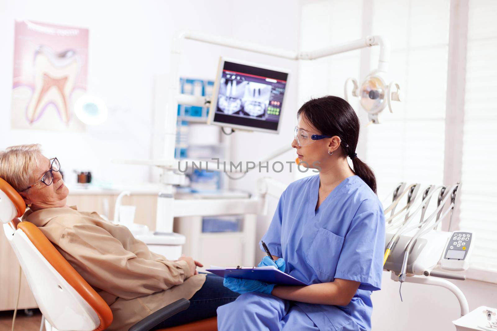 Dental assistant completing questioner during oral checkup by DCStudio