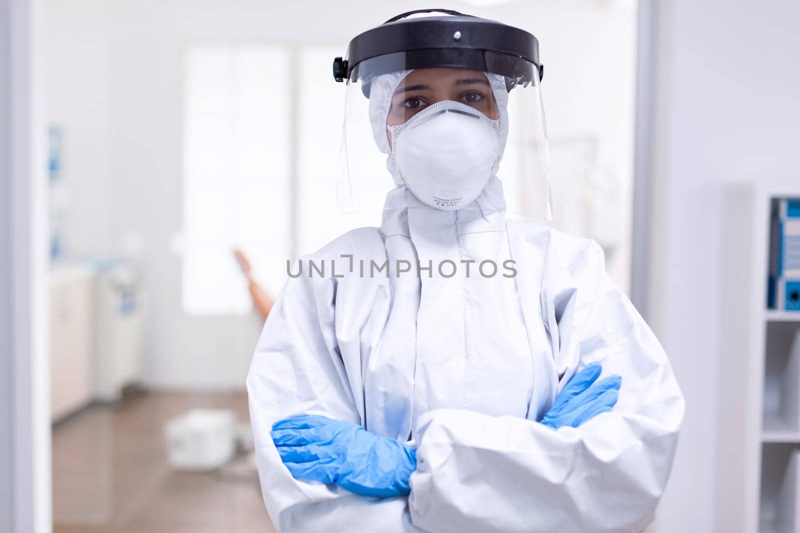 Stressed doctor with arms crossed in hazmat suit during coronavirus outbreak. Medical personal dressed in protection equipment against infection with covid-19 during global pandemic.