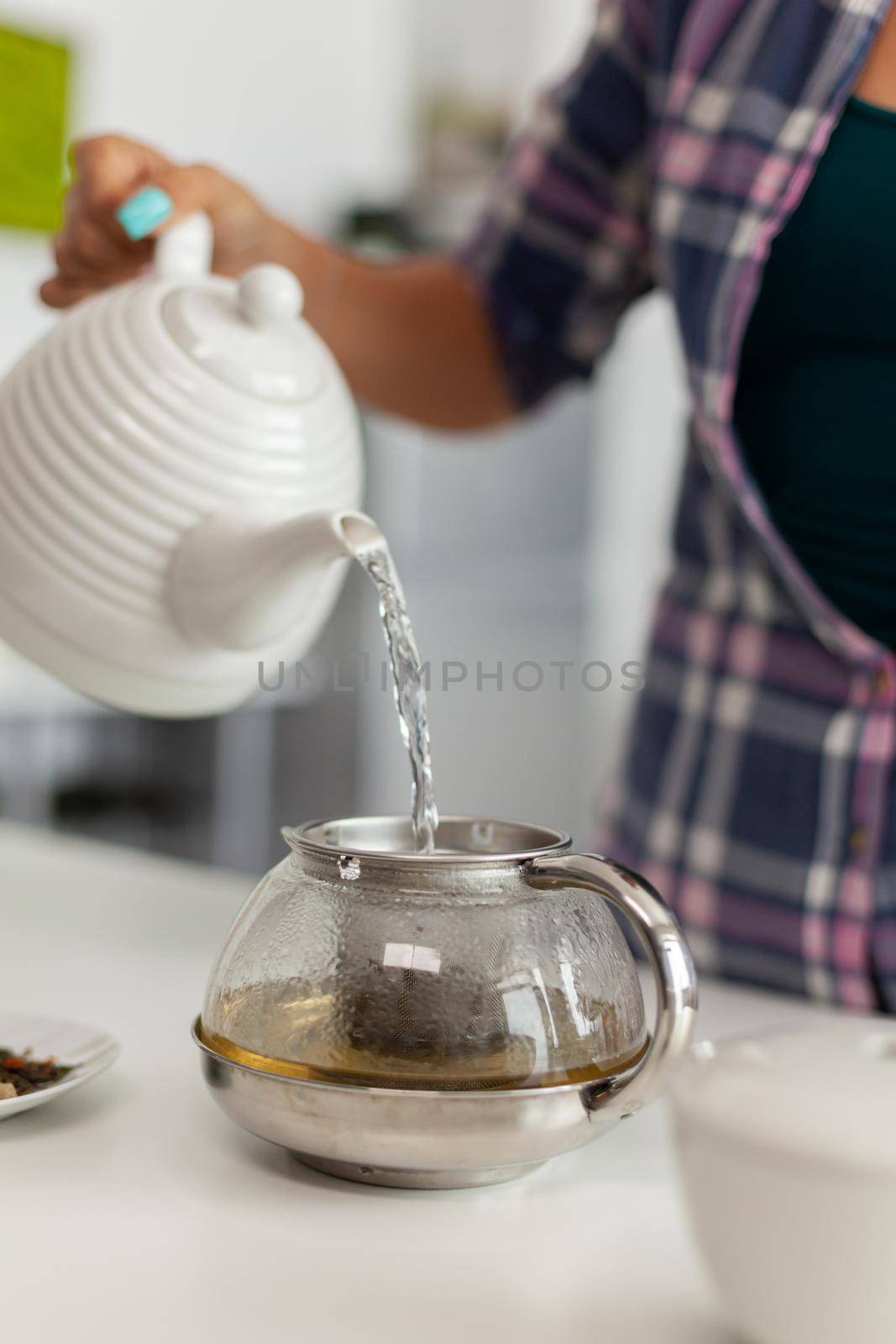 Lady making hot tea using natural herbs to enjoying breakfast in kitchen. Woman, lifestylem, beverage, preparation, herbal, teapot, morning, aromatic.