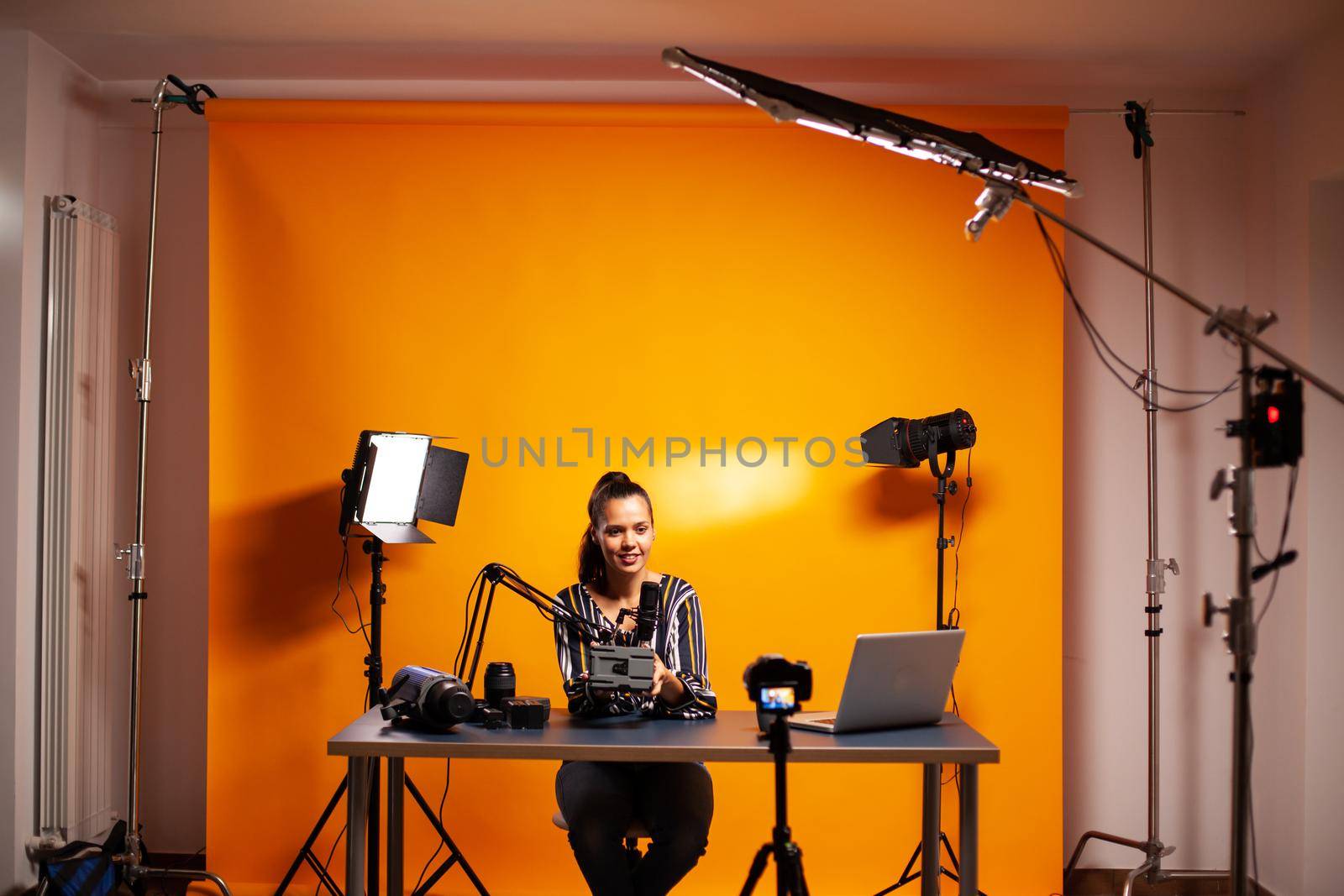 Videographer showing battery with v-mount in home studio for podcast. Professional videography gear review by content creator new media star influencer on social media.