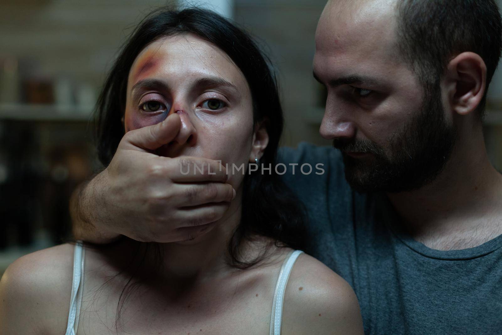 Close up of domestic violence couple fighting having relationship issues. Caucasian man in conflict with abused woman at home. Victim in cruel aggresive marriage having bruises on face