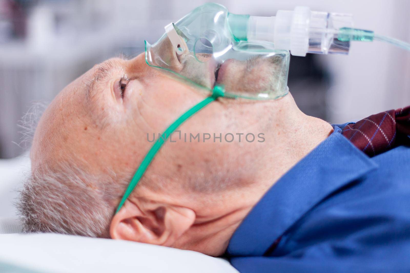 Old man breathing with oxygen mask in hospital bed during coronavirus pandemic. Medicine medical healthcare system epidemic lungs infection treatment