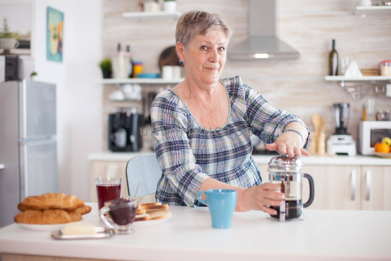 Portrait of old lady making french press coffee by DCStudio