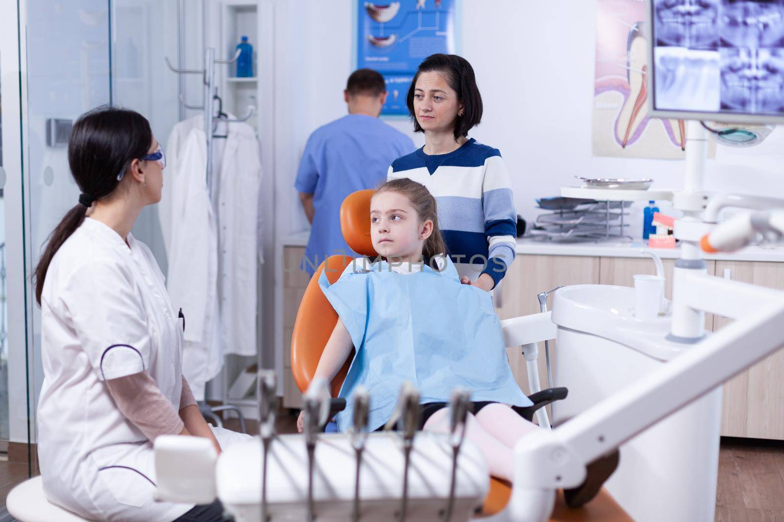 Parent with little girl listening pediatric dentist talking about mouth hygine by DCStudio
