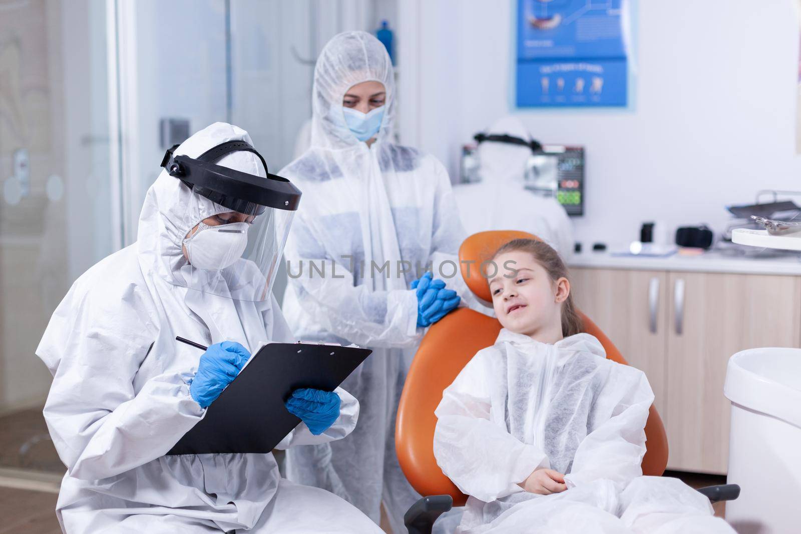 Orthodontist specialist writing treatment dressed in coverall by DCStudio