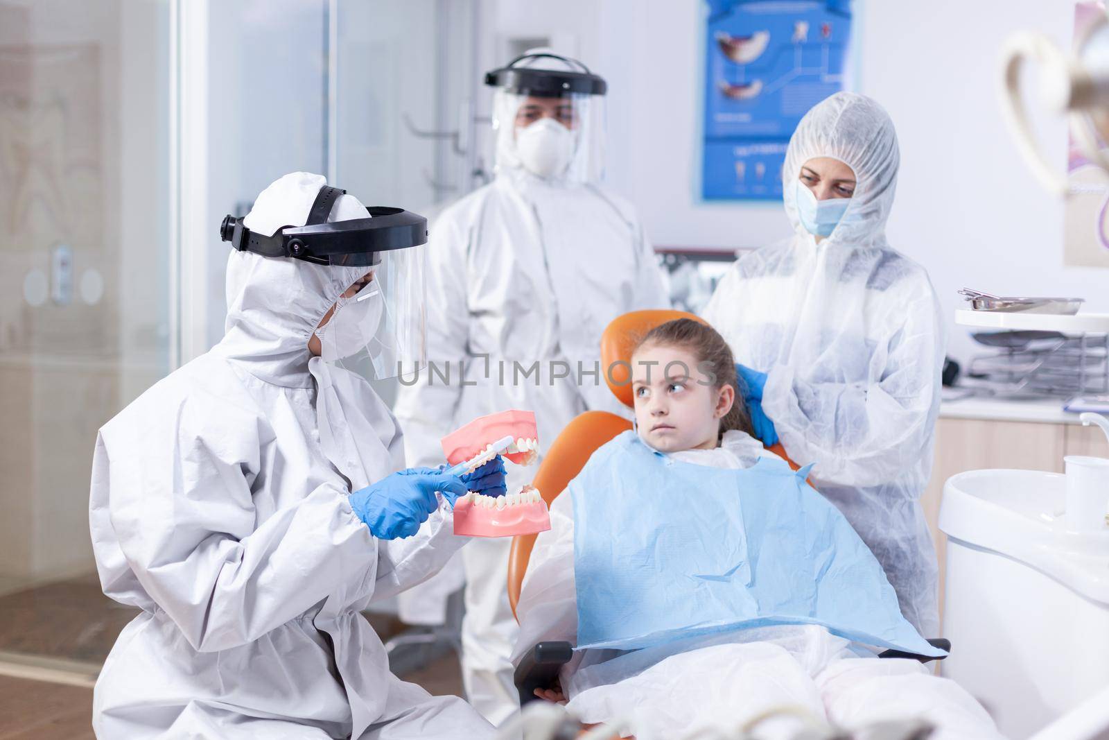 Child looking scared at parent sitting in dental chair by DCStudio