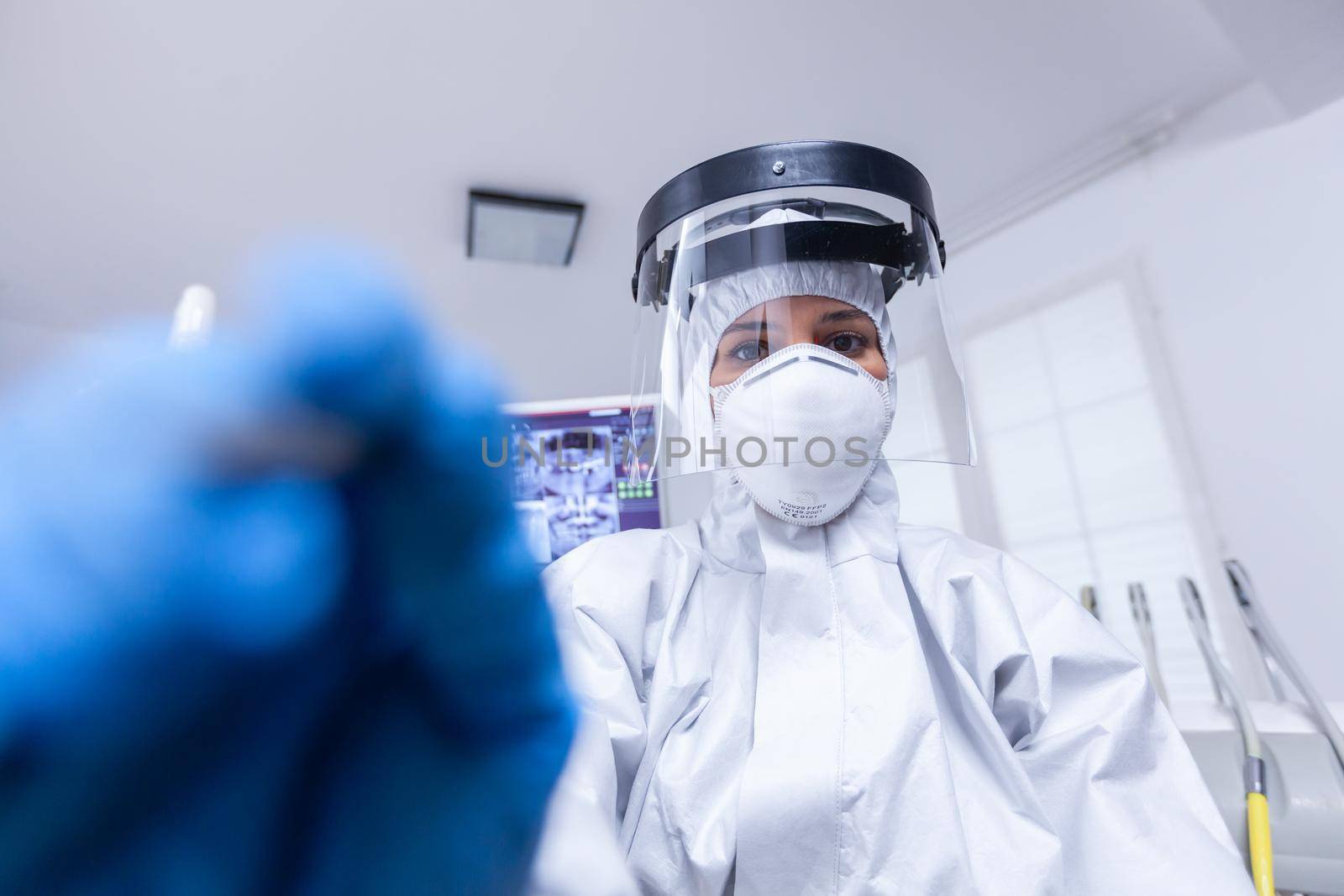 First person view of dentist preparing for teeth examination in hazmat suit agasint covid. Stomatolog wearing safety gear against coronavirus during heatlhcare check of patient.