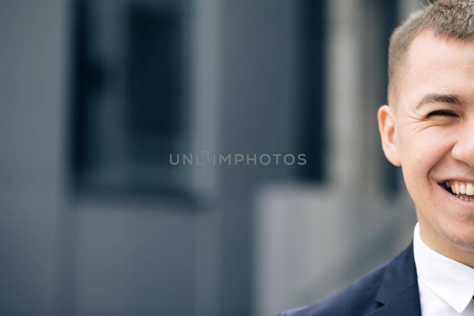 Close up of half face of handsome happy caucasian man with smile. Portrait of businessman. Happiness concept. Male smiling to camera cheerfully outdoors.