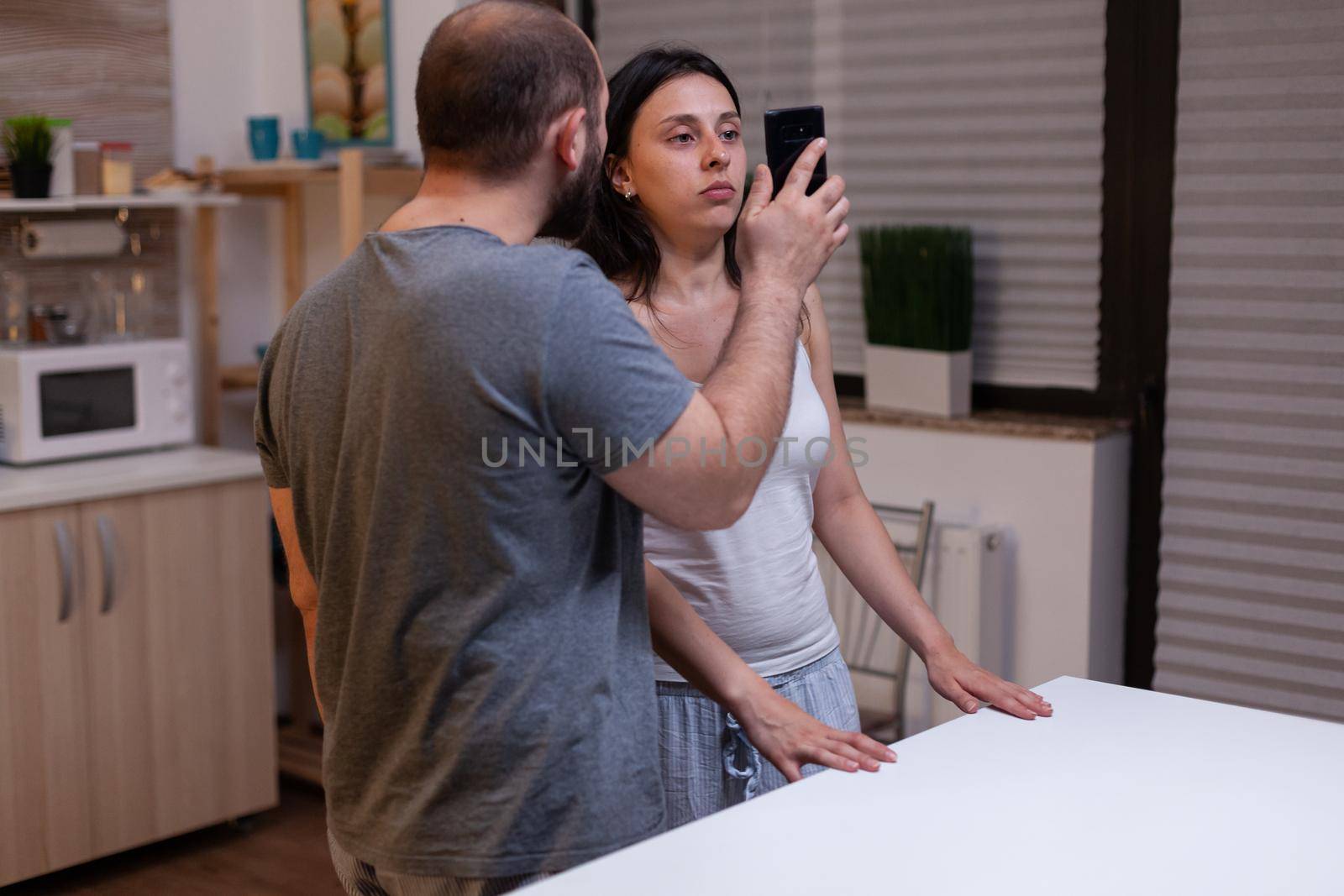 Angry jealous husband cheated by unhappy wife, couple fighting because of secret text messages with lover. Man showing smartphone with cheating proof to woman. Marriage infidelity.