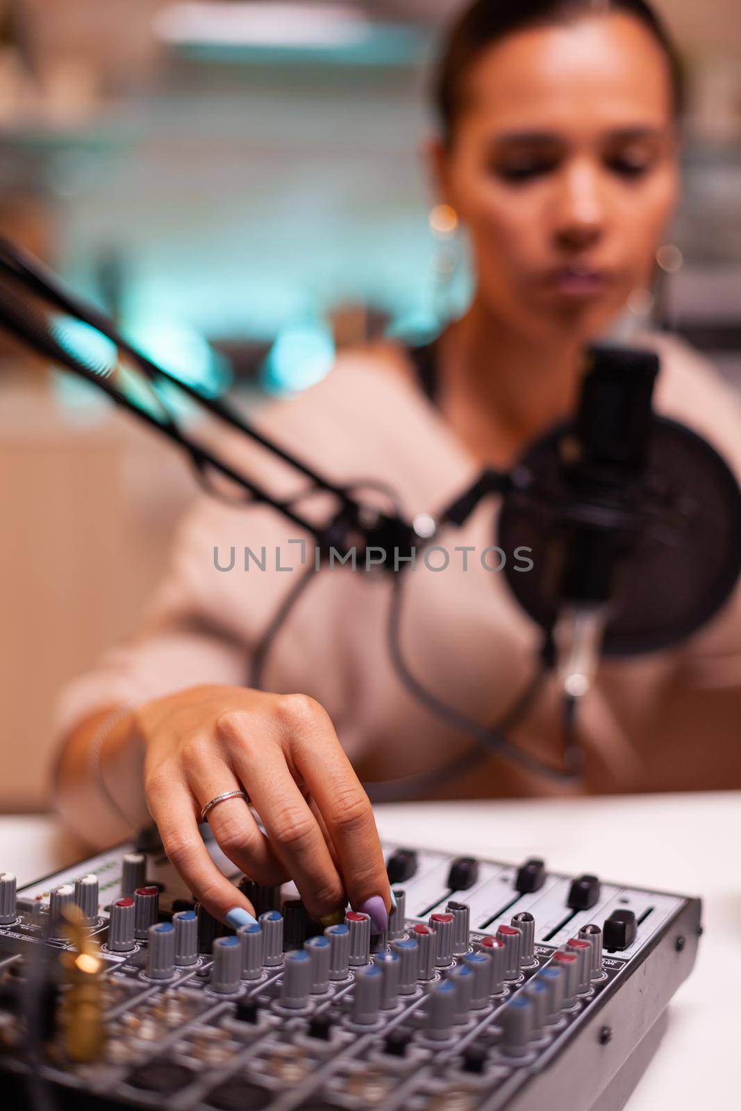 Influencer in entertainment industry smiling and checking sound during broadcast from home studio in the night. Recording digital social media communication