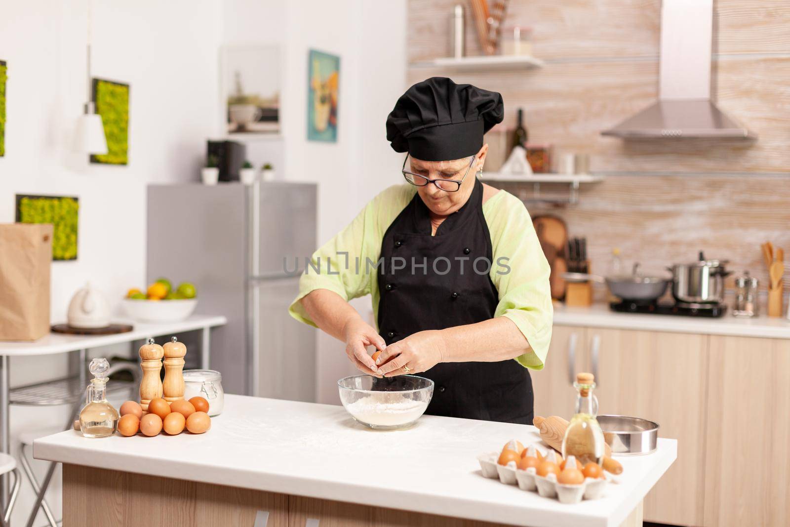 Woman breaks egg above flour by DCStudio