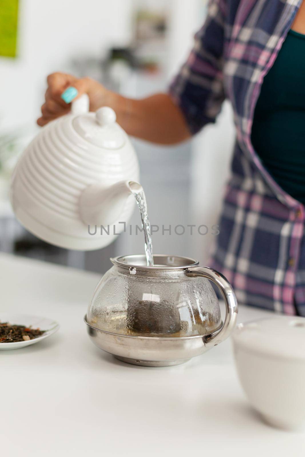 Close up of pouring hot water over natural aromatic herbs to make tea. Woman, lifestylem, beverage, preparation, herbal, teapot, morning, aromatic, lifestyle