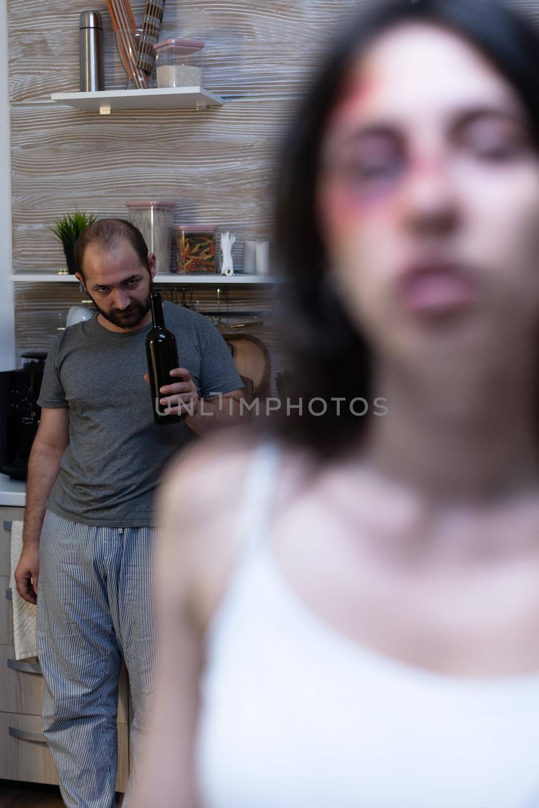 Woman having domestic violence bruises from partner while alcoholic angry man threatening to beat and fight. Couple with aggression issues feeling depressed in relationship, marriage