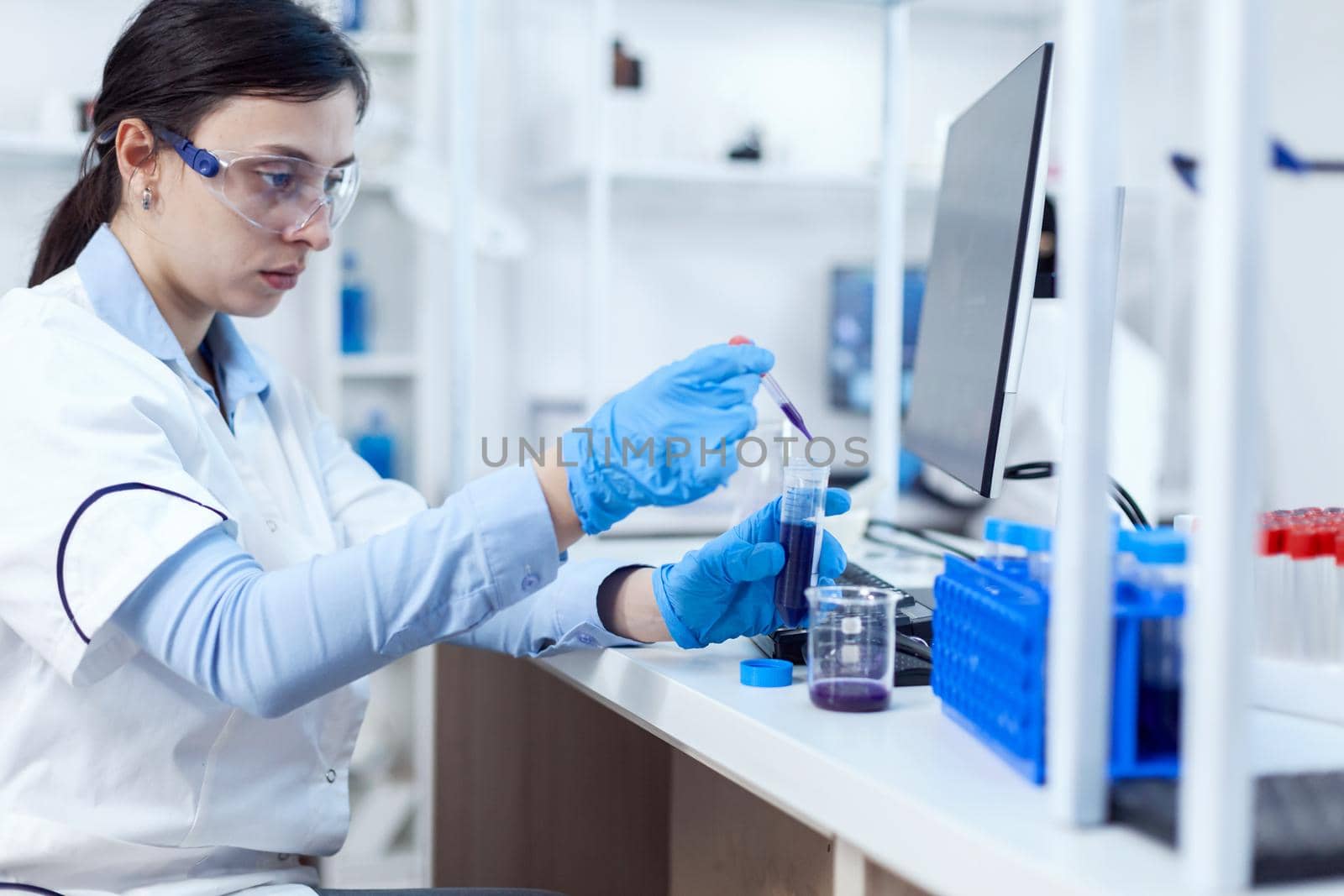 Woman scientist in lab during clinic experiement taking sample of genetic material by DCStudio