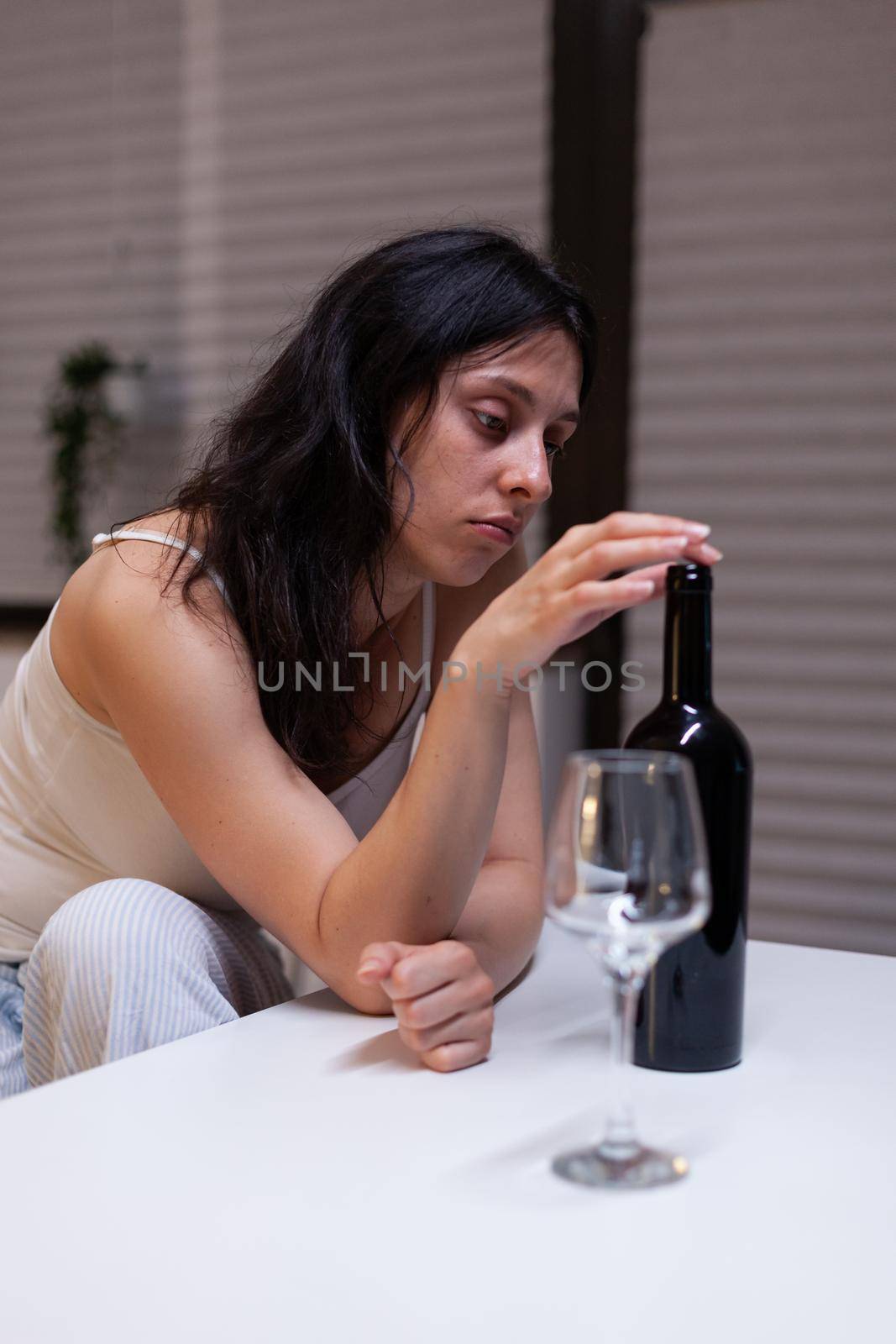 Young adult drinking wine alone in kitchen at home by DCStudio