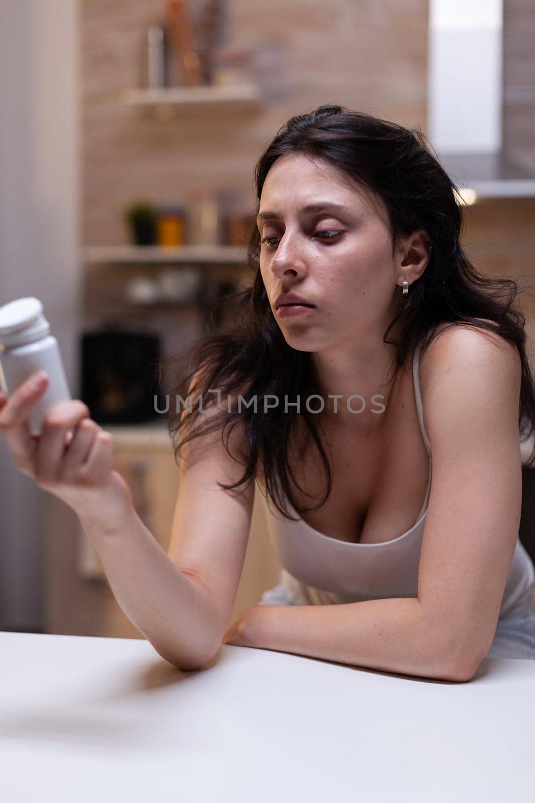 Caucasian woman with headache holding bottle of pills by DCStudio