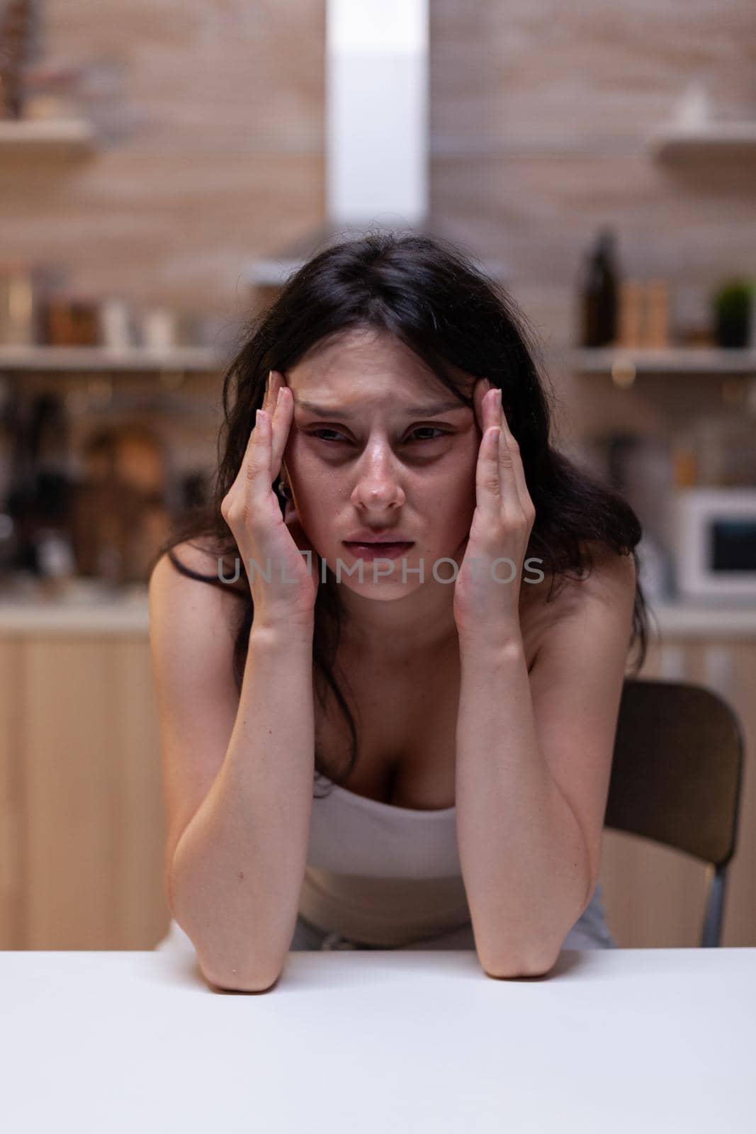 Portrait of upset woman with serious headache pain holding hand on temples because of stress. Person feeling depressed at home having migraine from fatigue and depression problems