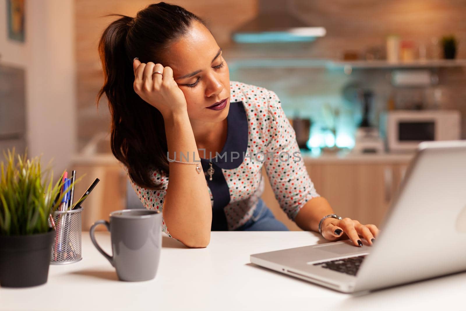 Overworked woman falling asleep in home kitchen by DCStudio