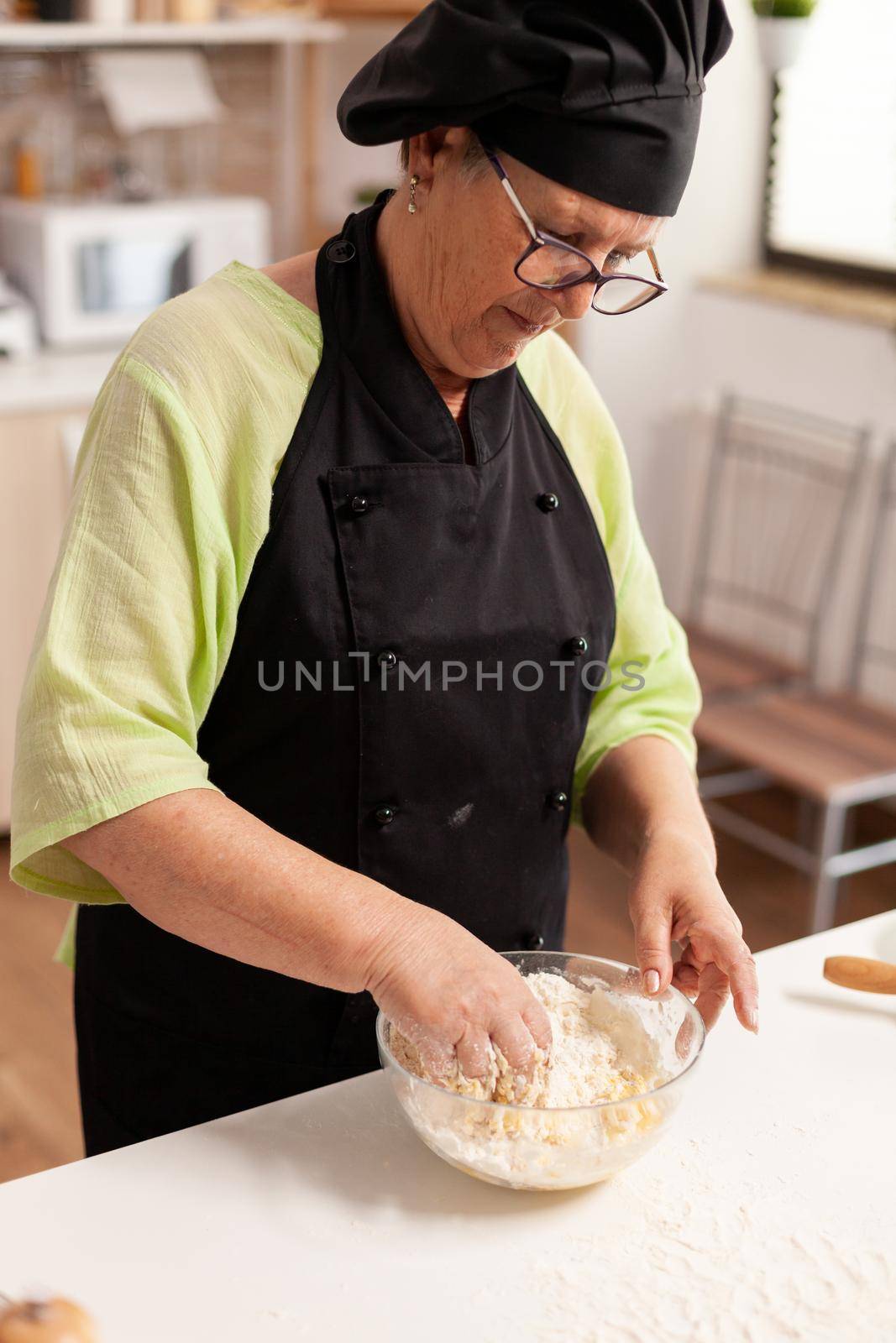 Chef hand in wheat flour with eggs in home kitchen for traditional pasta. Retired elderly chef with uniform sprinkling, sieving sifting raw ingredients and mixing.