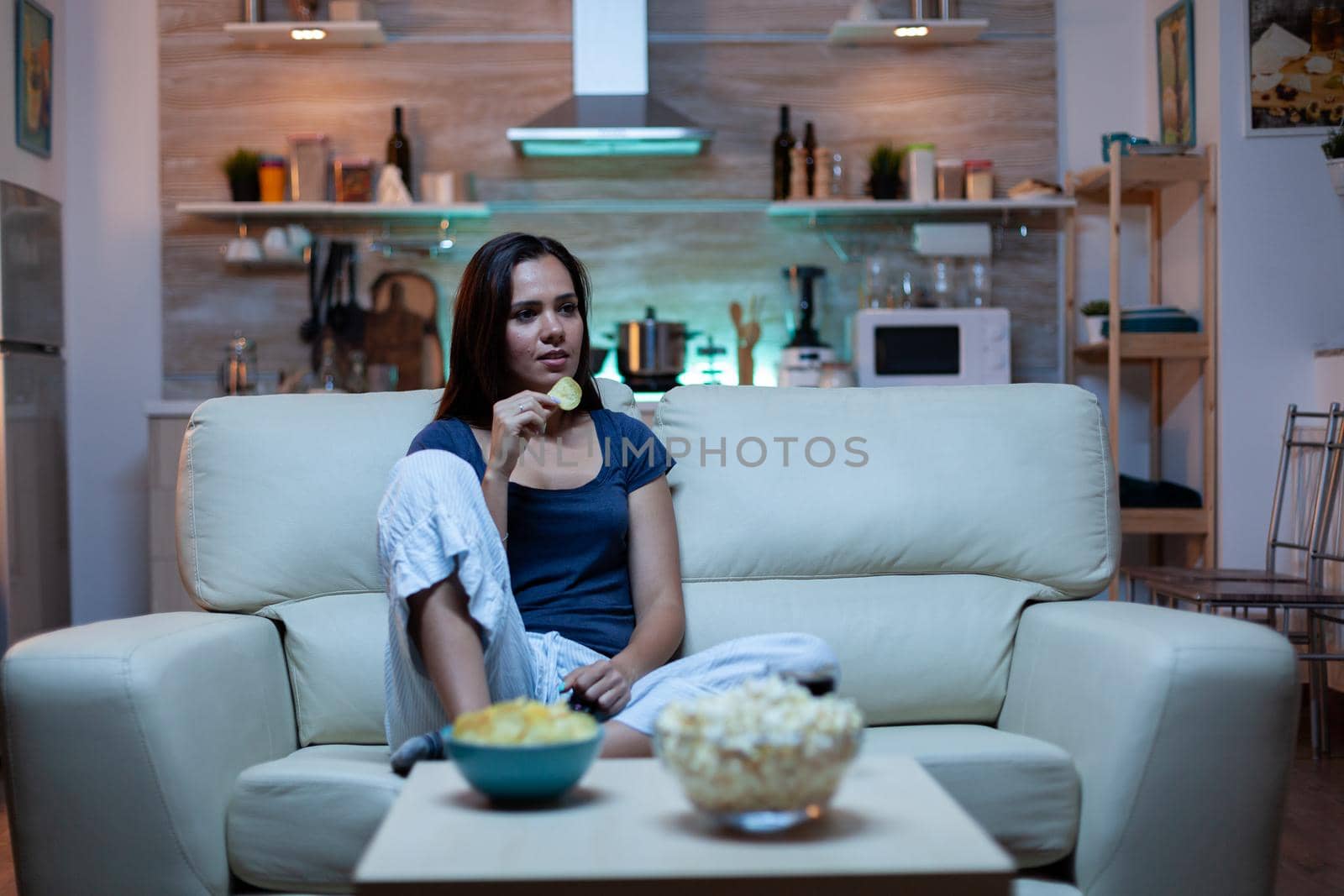 Housewife eating snacks on sofa by DCStudio