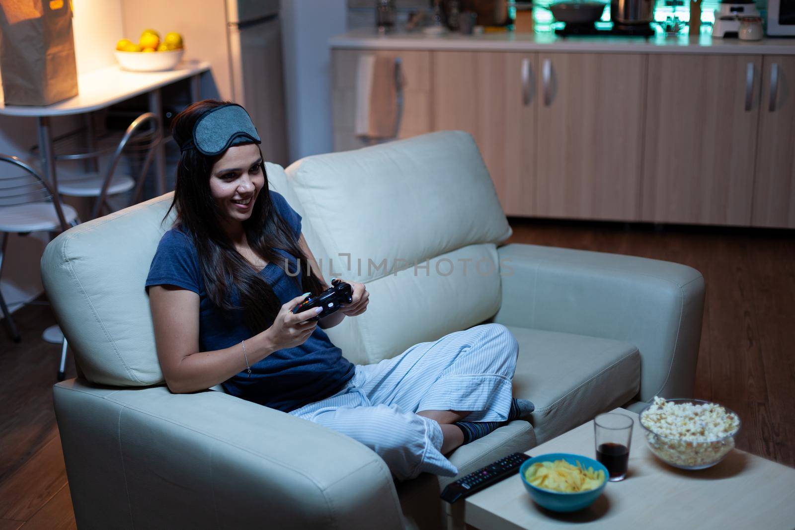 Woman sitting on sofa playing video games, smiling relaxing enjoying the evening. Excited determined gamer using controller joysticks keypad playstation gaming and having fun winning electronic game