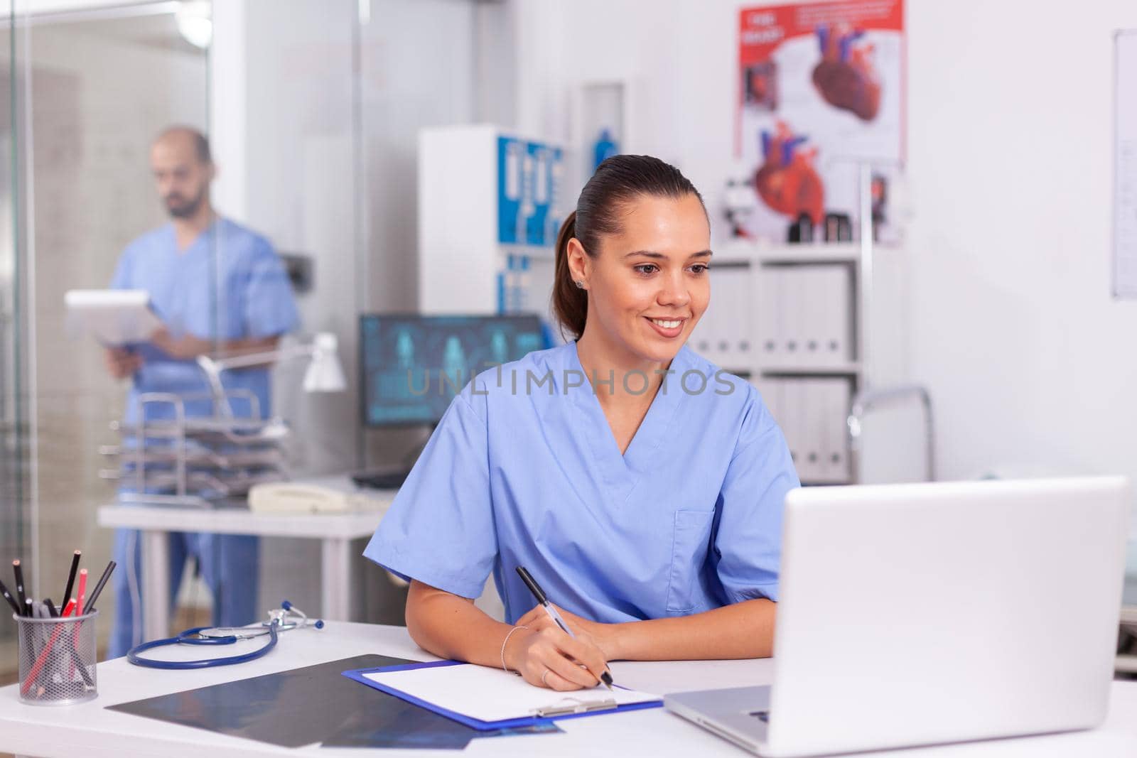 Smiling nurse using laptop computer by DCStudio